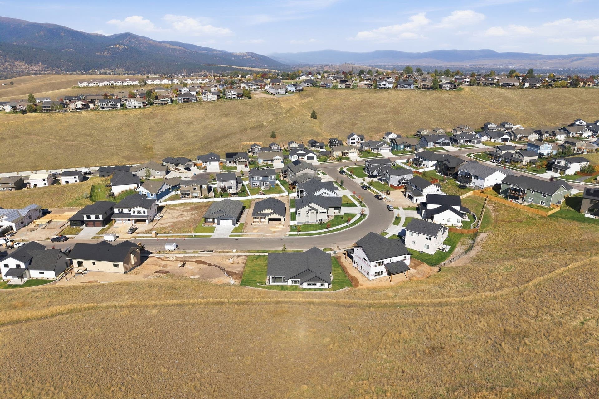 Residential development featuring multiple homes, paved roads, and natural landscape