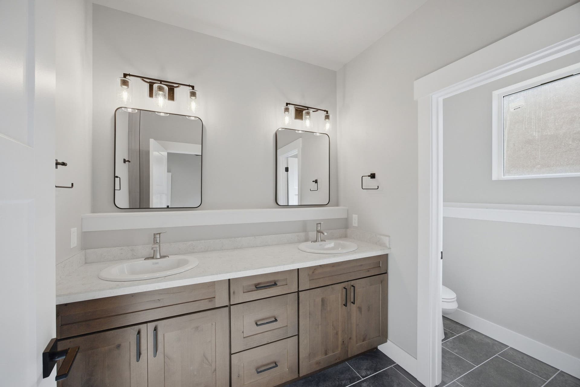 Dual-sink vanity with wood-finish cabinetry, white quartz countertop, and brushed nickel faucets