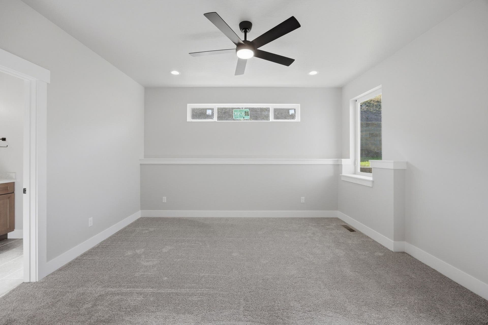 Expansive carpeted room featuring a ceiling fan with integrated lighting, recessed lighting, and multiple windows