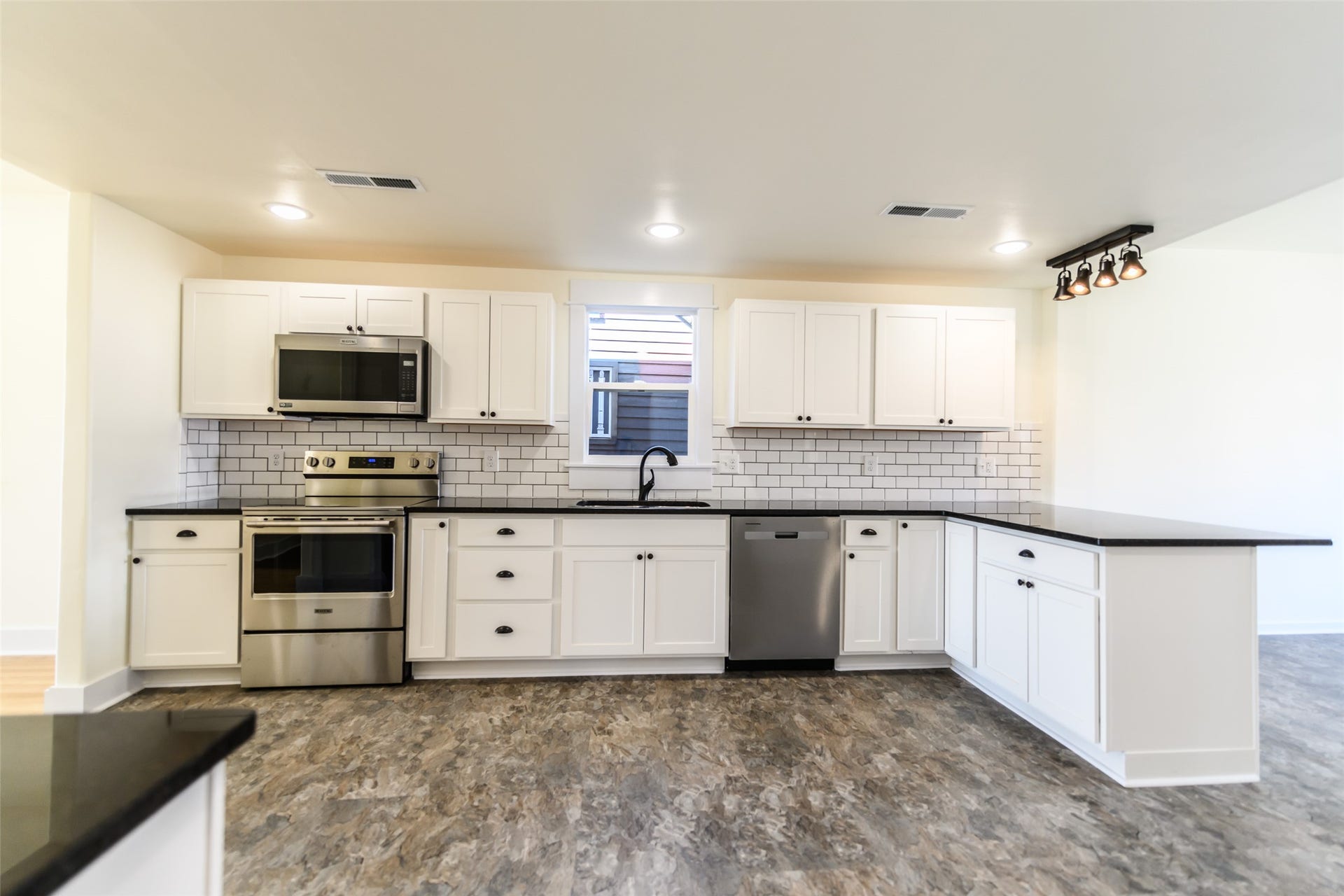 705 W Park Street, Butte, MT 59701 Kitchen featuring white cabinetry, dark countertops, stainless steel appliances, a white subway tile backsplash, and wood-finish flooring