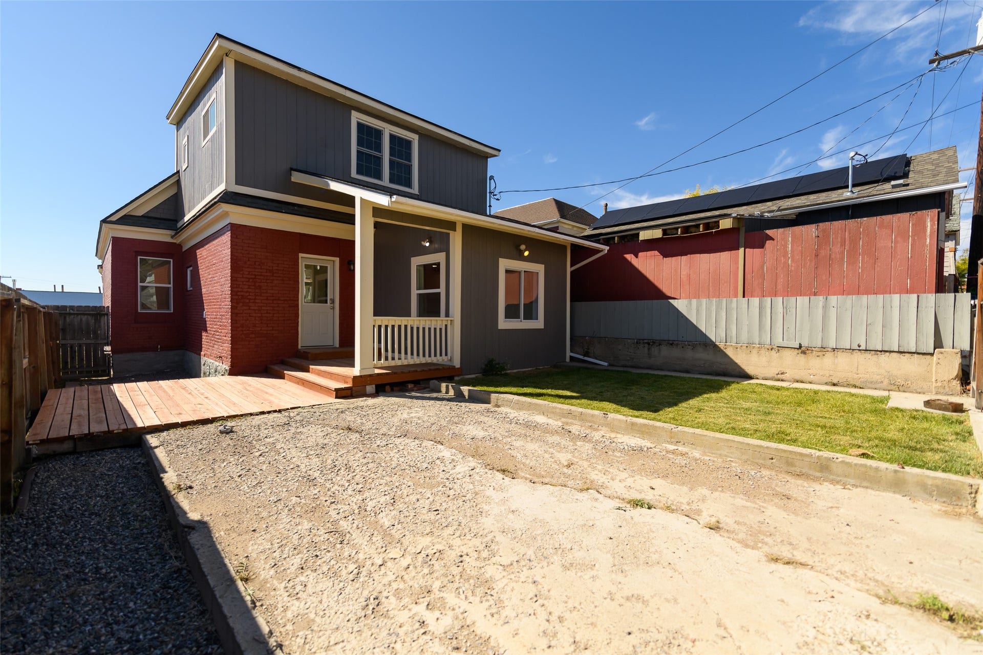 705 W Park Street, Butte, MT 59701 Rear exterior featuring a red brick facade, gray siding, a covered porch with white railing, and a new wood deck