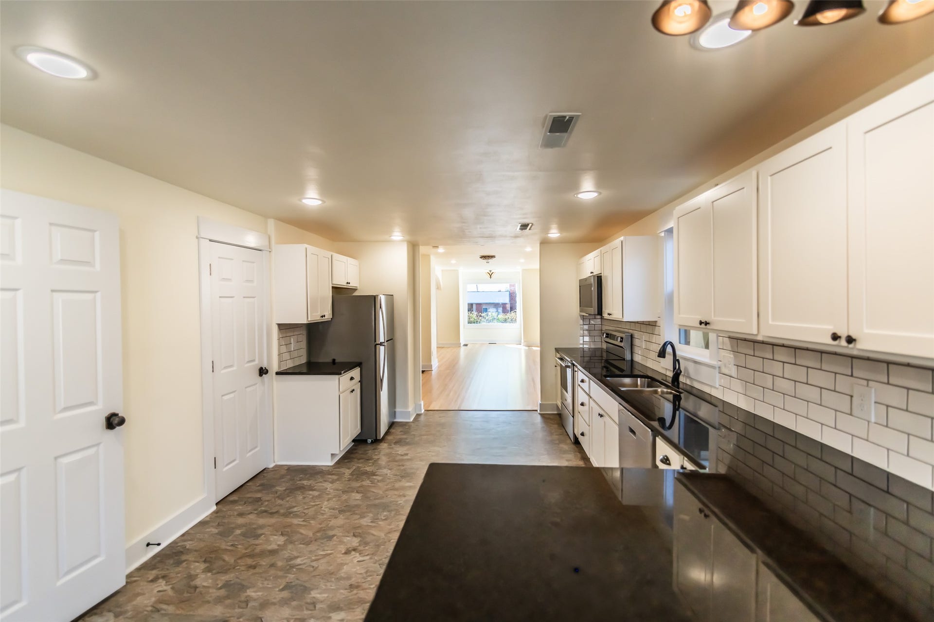 705 W Park Street, Butte, MT 59701 Kitchen featuring white cabinetry, dark countertops, a subway tile backsplash, and stainless steel appliances