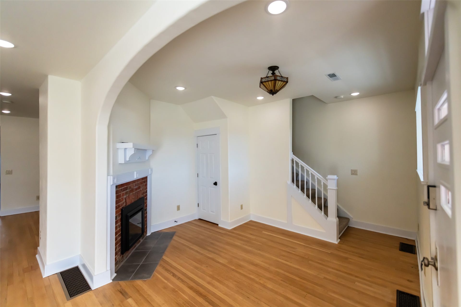 705 W Park Street, Butte, MT 59701 Hardwood flooring, arched doorway, brick fireplace with mantel, recessed lighting, and white staircase with wood railings