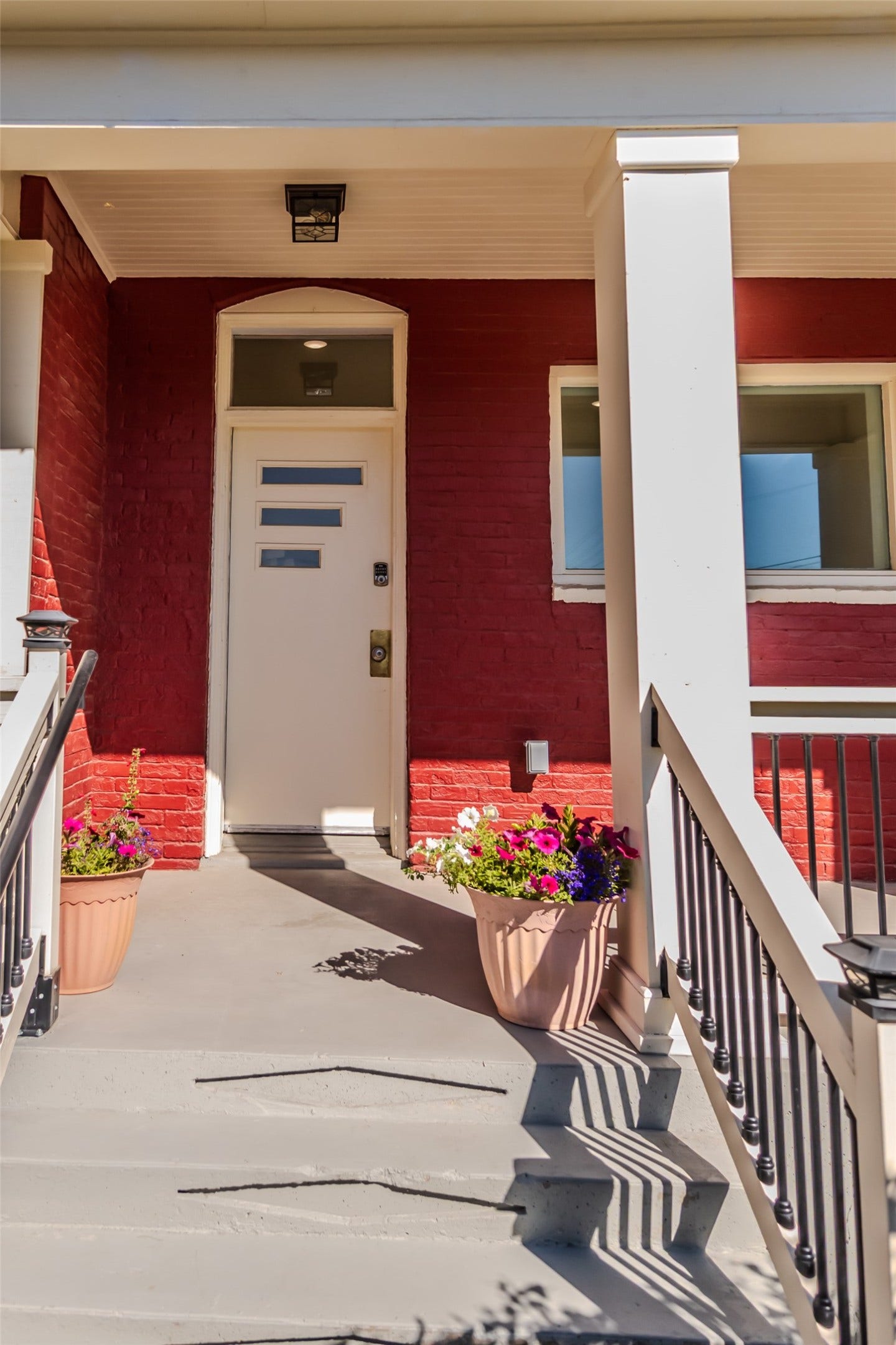 705 W Park Street, Butte, MT 59701 Red brick exterior with white trim, modern white entry door, covered porch with white columns, and concrete steps with railings