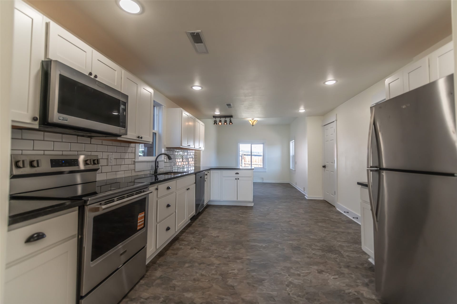 705 W Park Street, Butte, MT 59701 Kitchen featuring white cabinetry, black countertops, a subway tile backsplash, and stainless steel appliances