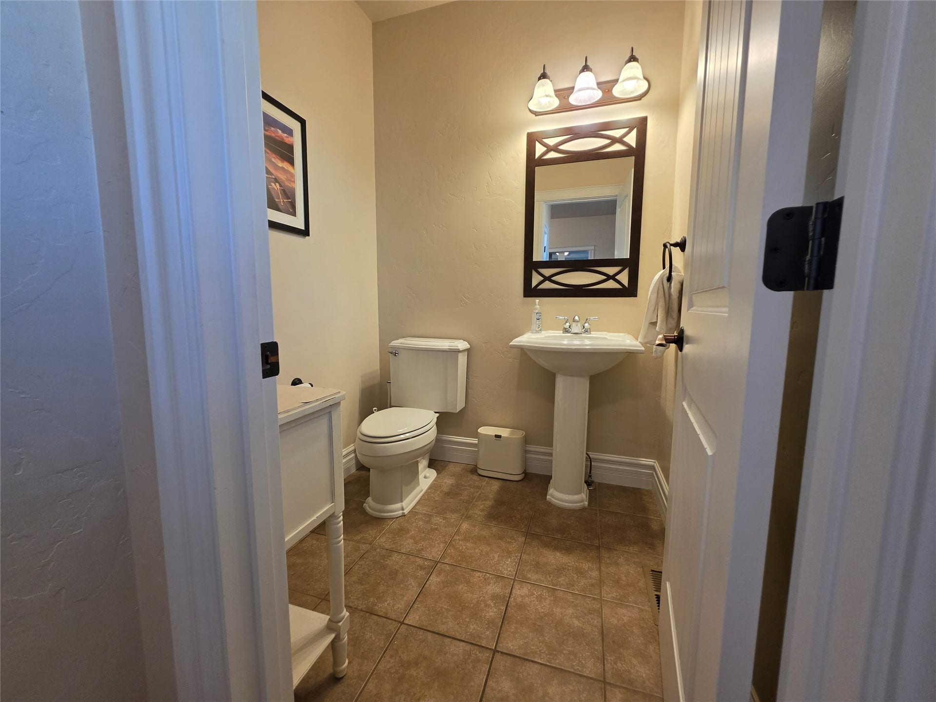 585 Wildflower Circle, Hamilton, MT 59840 Pedestal sink with a decorative framed mirror, three-light vanity fixture, and tiled flooring