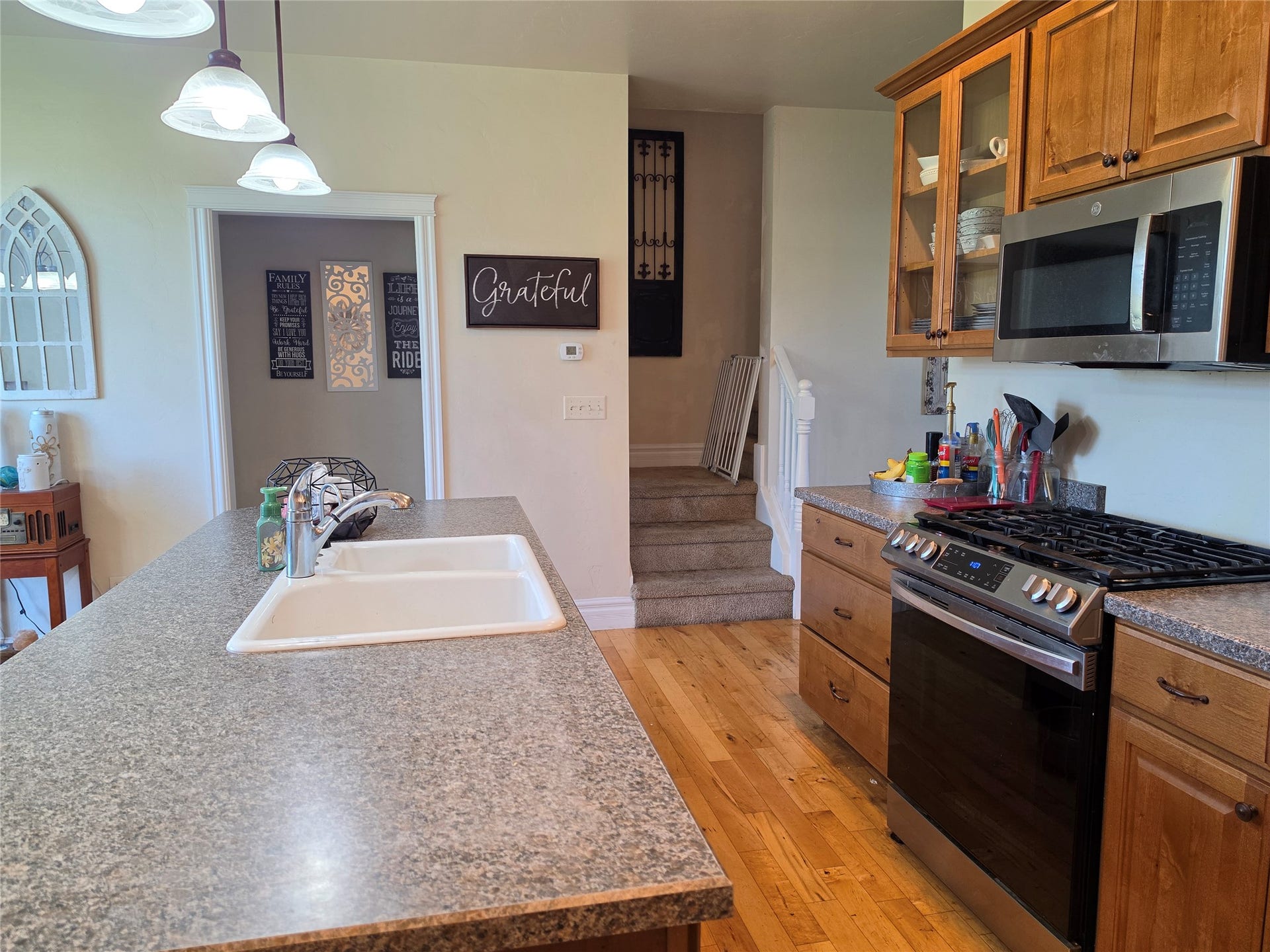 585 Wildflower Circle, Hamilton, MT 59840 Kitchen island with integrated sink, wood-finish flooring, stainless steel range, and wood cabinetry with glass-front uppers