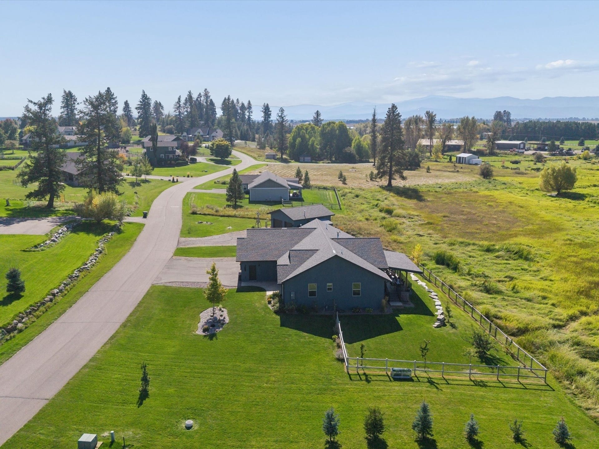 148 Fox Den Trail, Kalispell, MT 59901 Single-story residence featuring a dark-toned roof, expansive green lawn, and adjacent natural landscape
