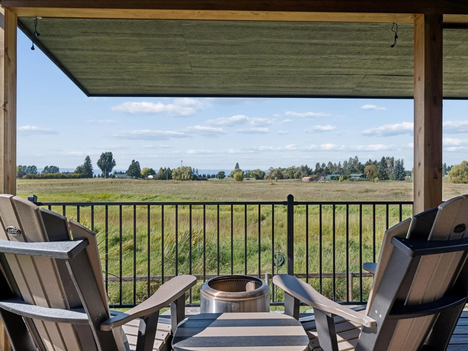148 Fox Den Trail, Kalispell, MT 59901 Covered outdoor deck with wood posts, black metal railing, and expansive fields