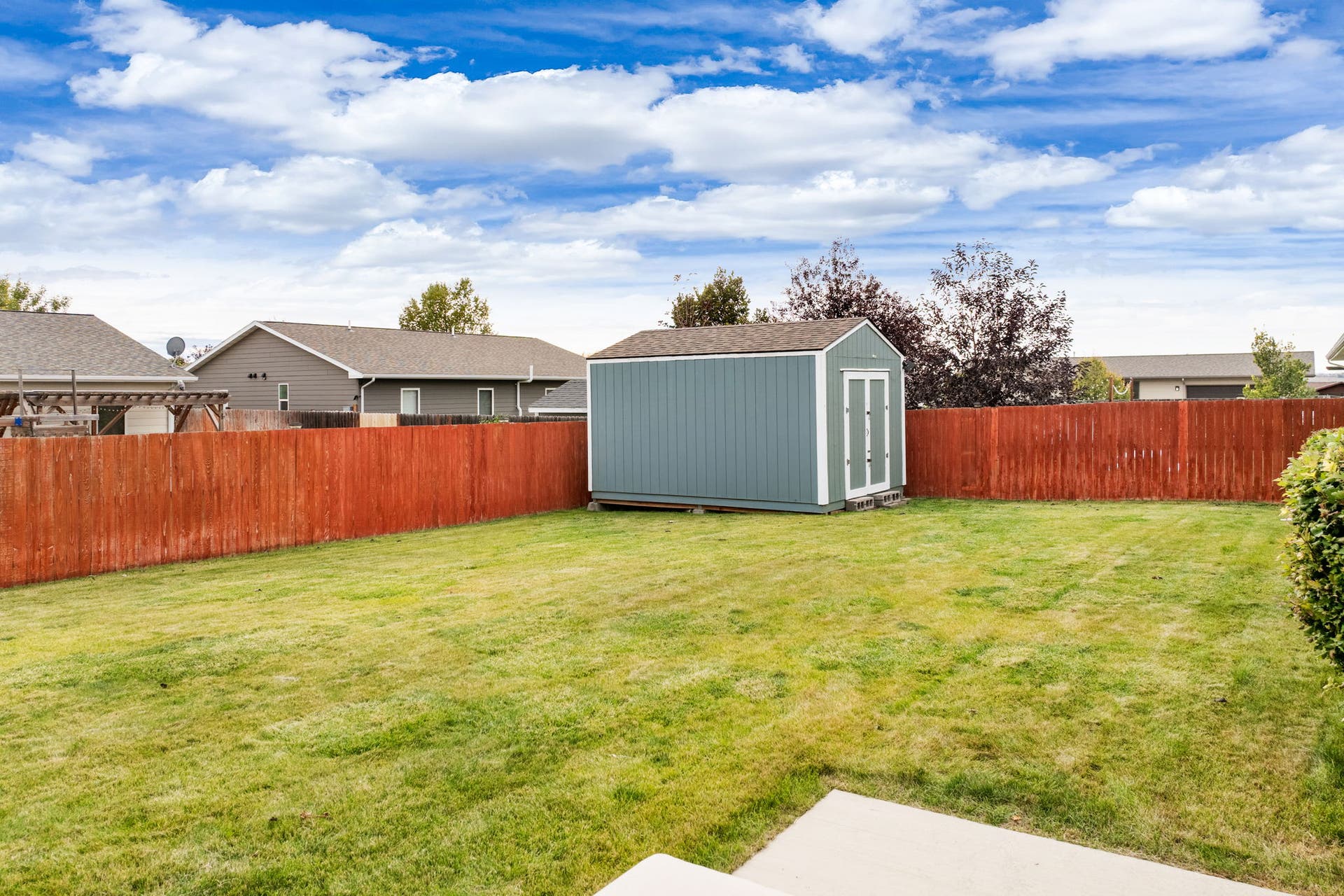 2541 Castle Pines Way, Great Falls, MT 59405 Expansive lawn area with a wood privacy fence and a detached storage shed