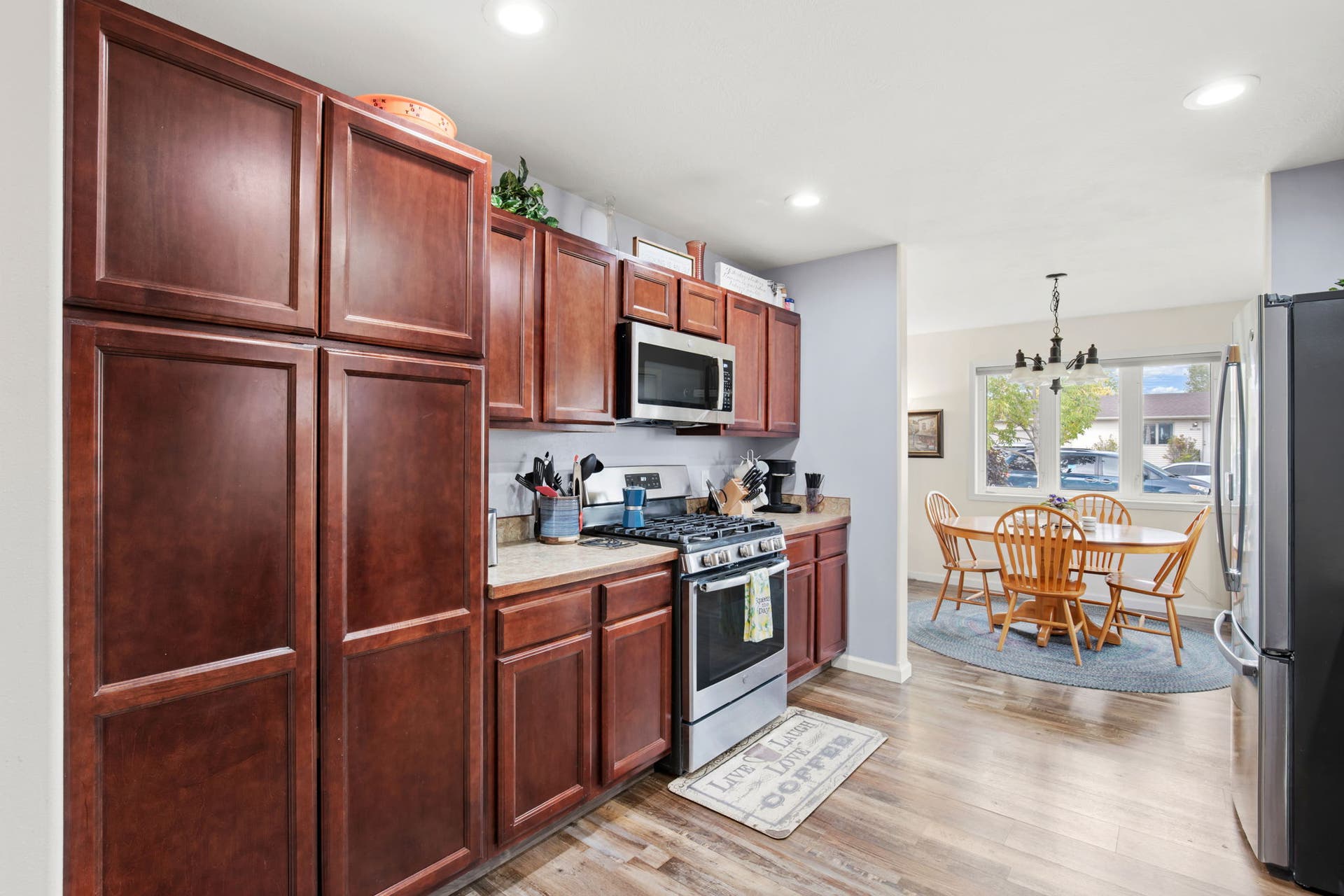 2541 Castle Pines Way, Great Falls, MT 59405 Full-height wood-finish cabinetry, stainless steel range with overhead microwave, wood-finish flooring, and recessed ceiling lighting