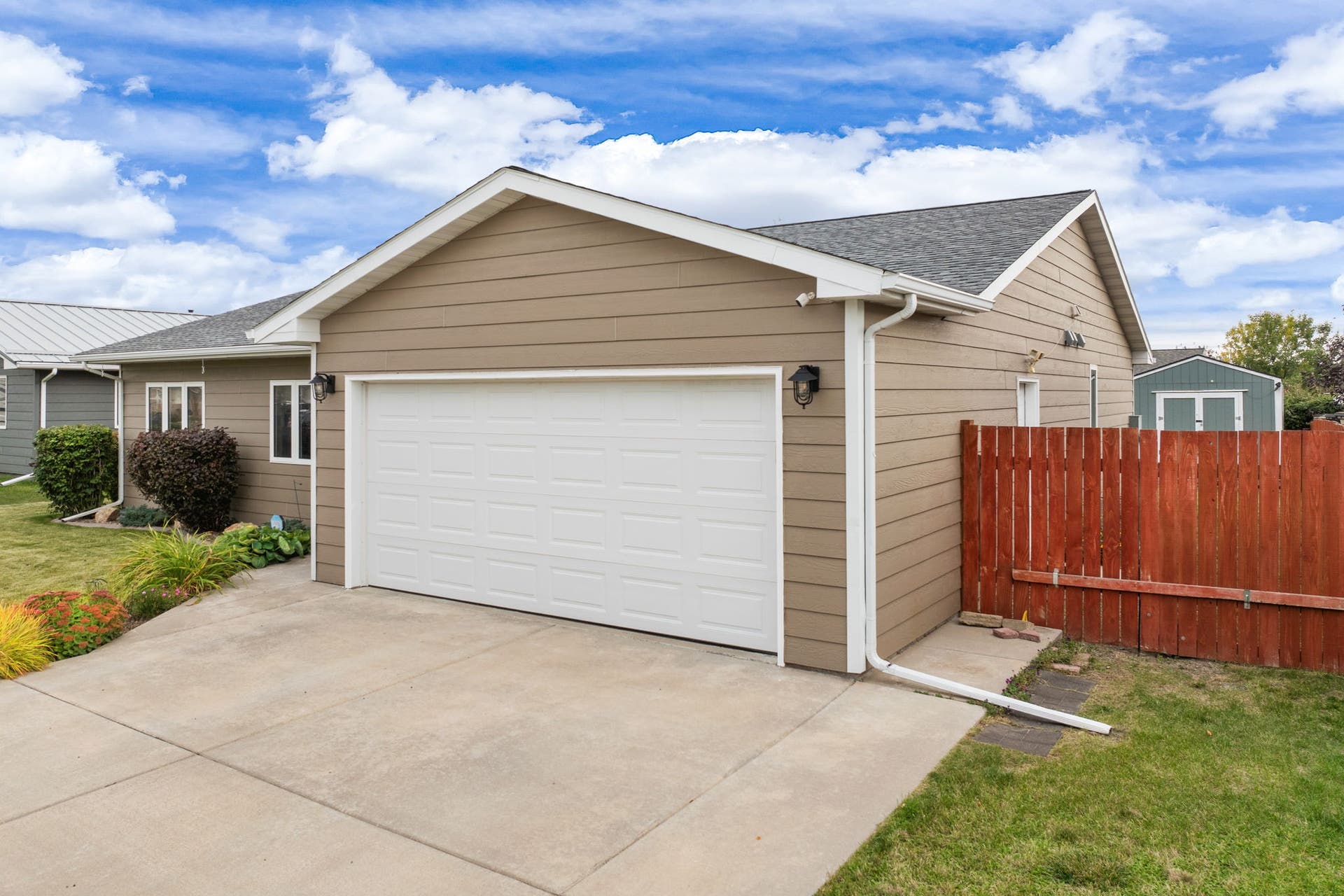 2541 Castle Pines Way, Great Falls, MT 59405 Attached garage with a panel door, concrete driveway, and tan siding