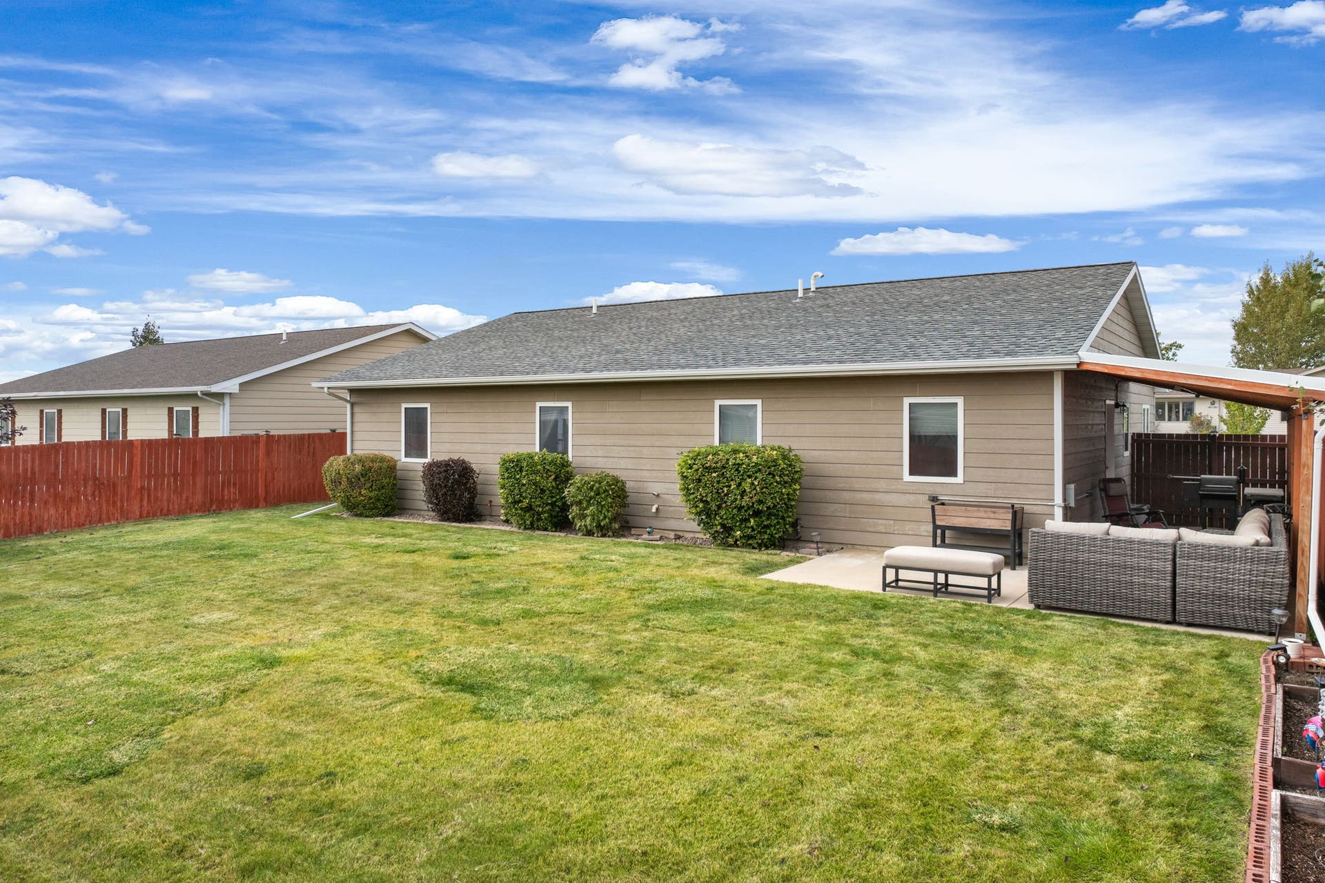 2541 Castle Pines Way, Great Falls, MT 59405 Expansive backyard featuring a manicured lawn, concrete patio, and a covered outdoor living area