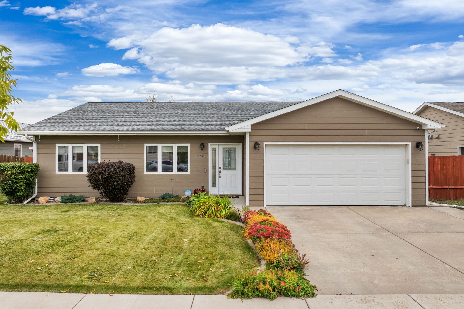 2541 Castle Pines Way, Great Falls, MT 59405 Siding exterior, attached two-car garage, concrete driveway, front yard with landscaping, and a shingled roof