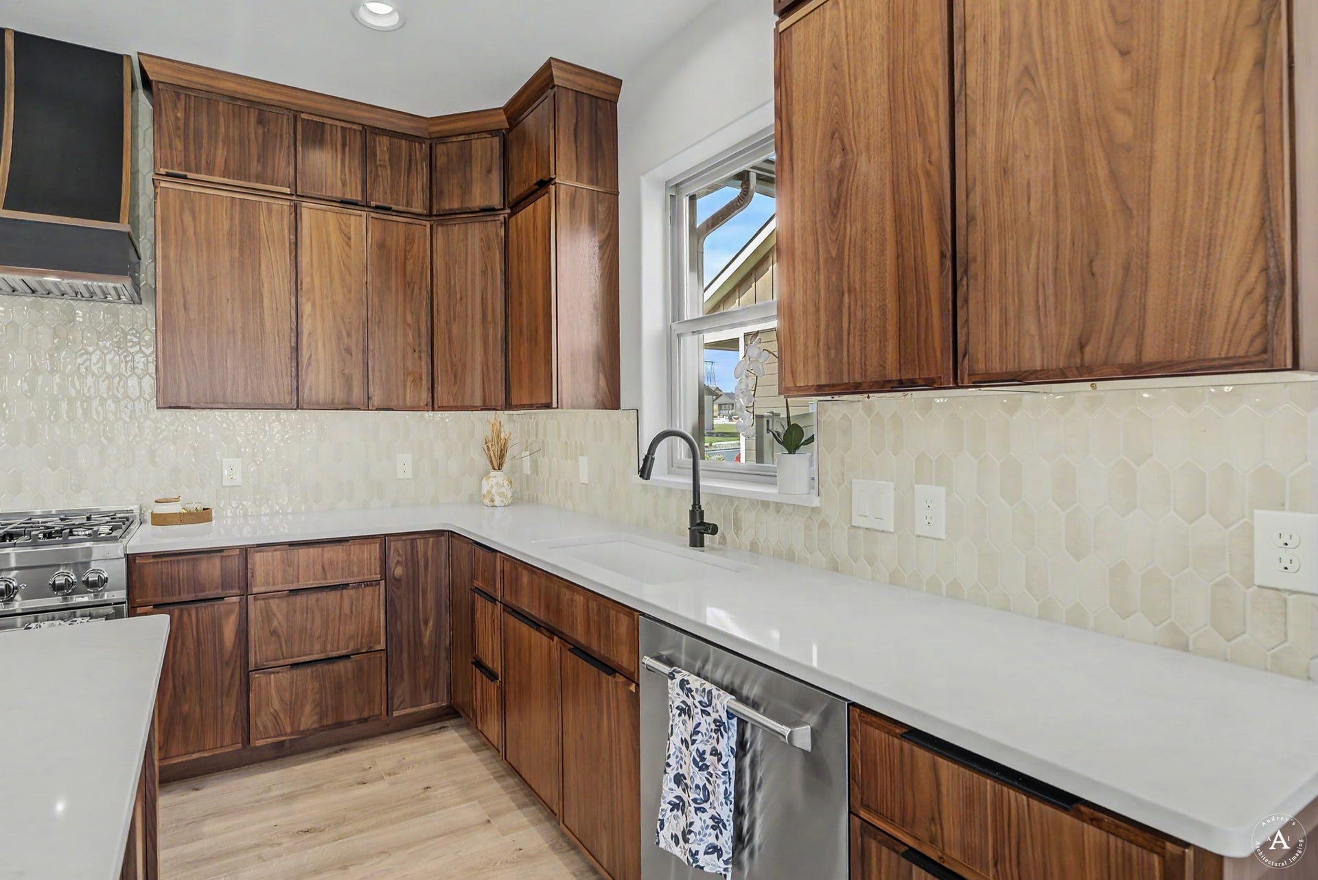 2754 Lone Chief Loop, Helena, MT 59601 Rich wood-finish cabinetry, light-toned countertops, a stainless steel gas range, a coordinating range hood, and a geometric tile backsplash