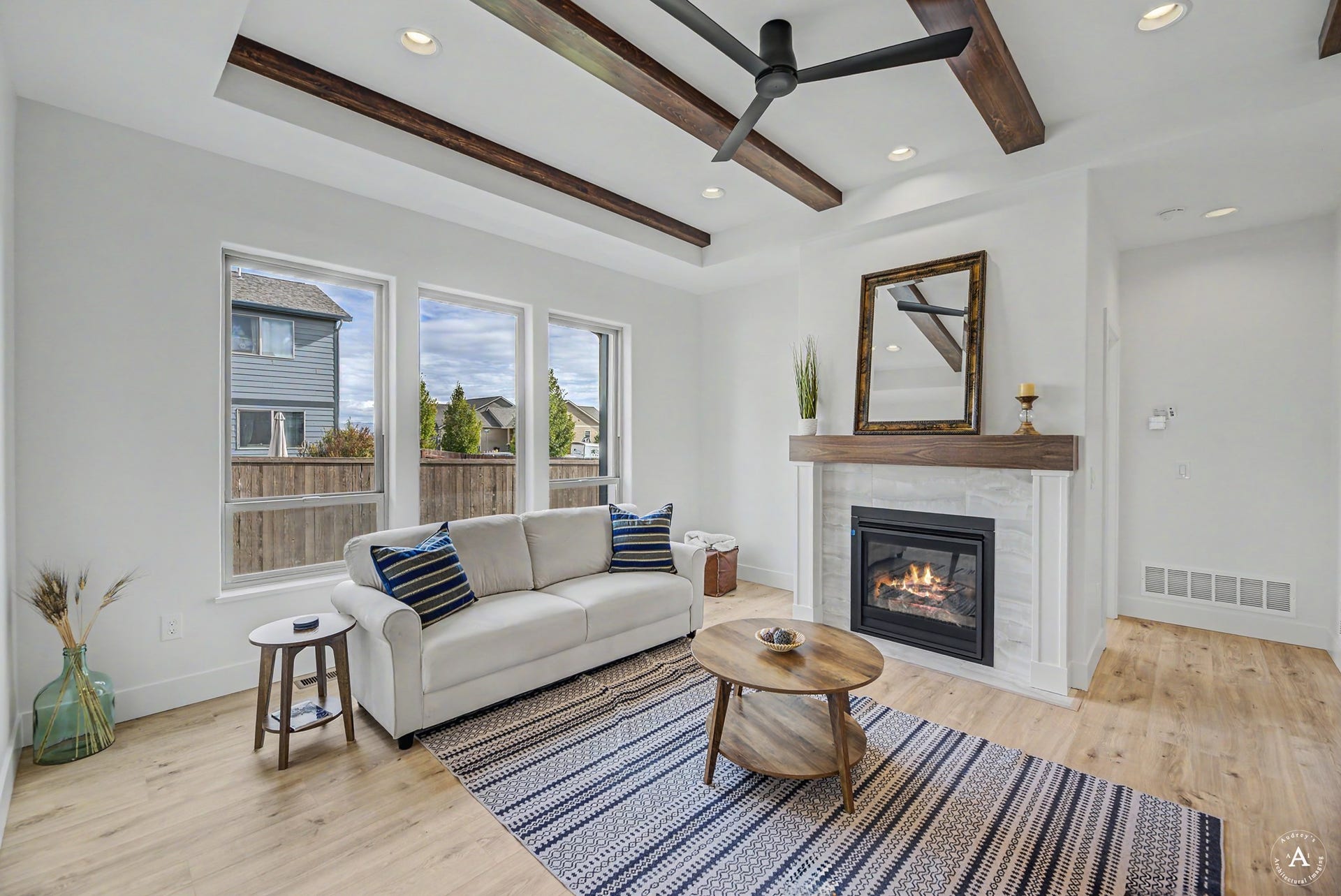 2754 Lone Chief Loop, Helena, MT 59601 Wood-finish flooring throughout, tray ceiling with exposed wood beams, modern ceiling fan, recessed lighting, and a fireplace with a wood mantle and tile surround
