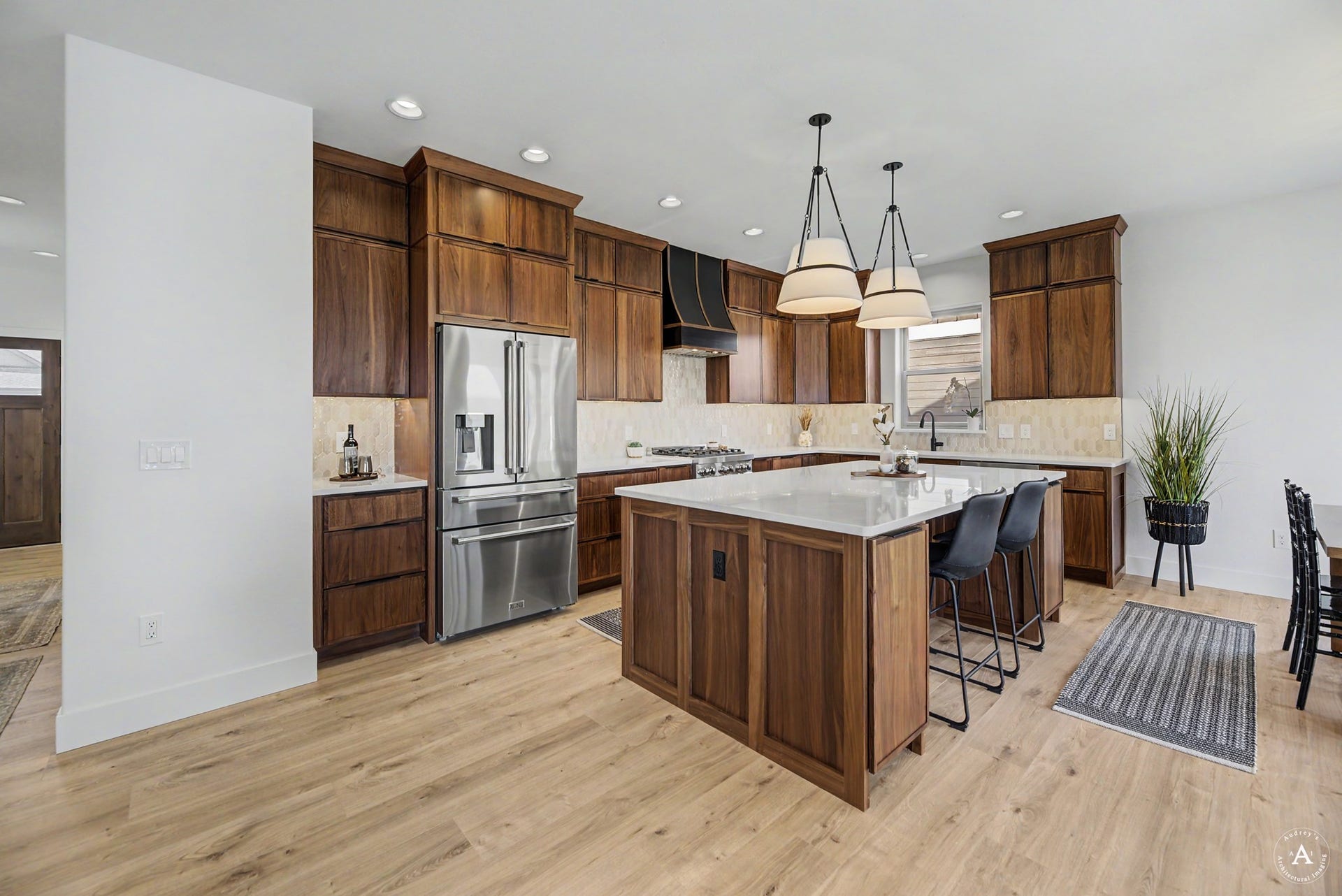 2754 Lone Chief Loop, Helena, MT 59601 Wood-finish flooring throughout, stainless steel refrigerator, dark wood cabinetry with crown molding, kitchen island with seating, and pendant lighting