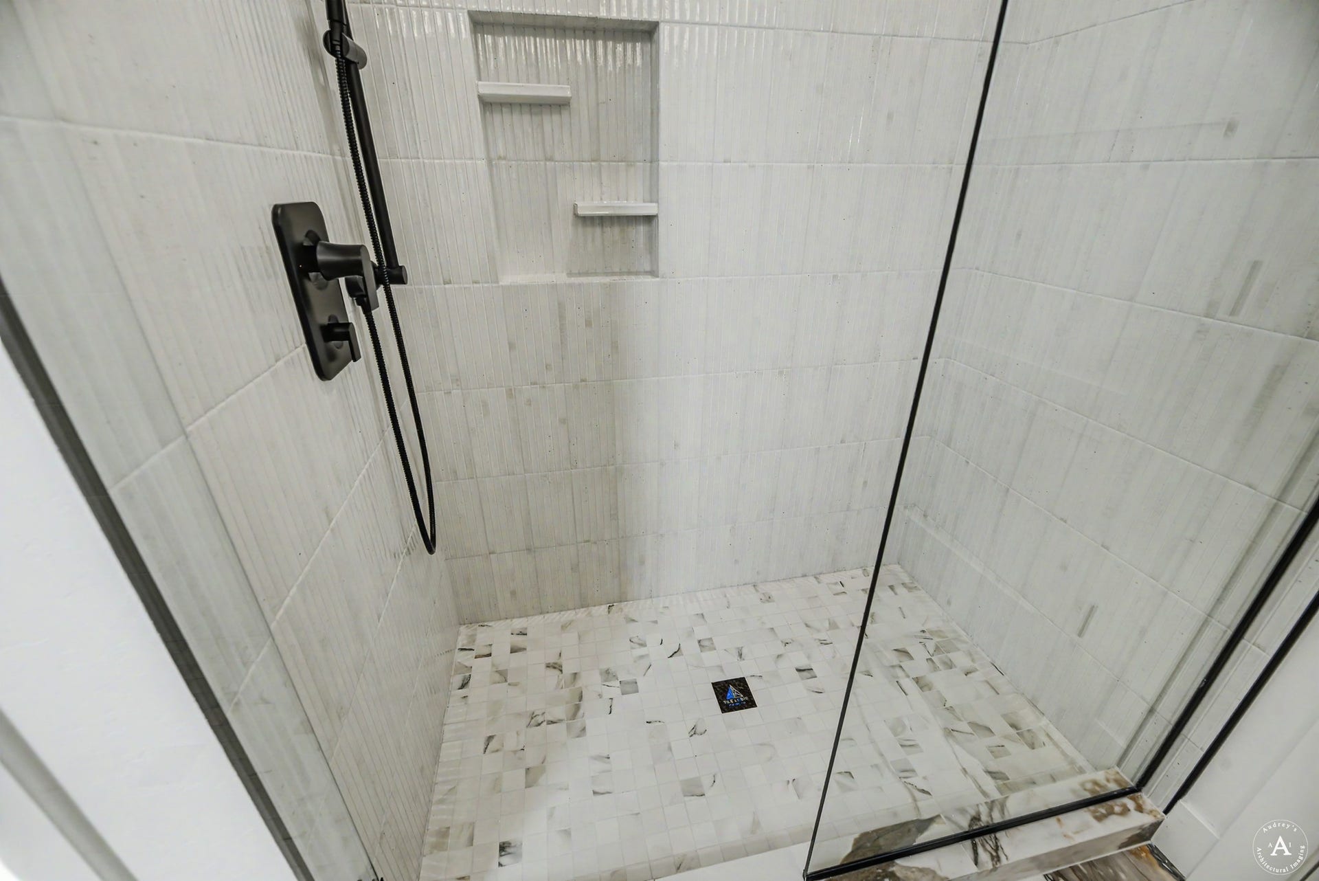 2754 Lone Chief Loop, Helena, MT 59601 Tiled shower featuring a built-in niche with shelving, black shower fixtures, and a glass enclosure
