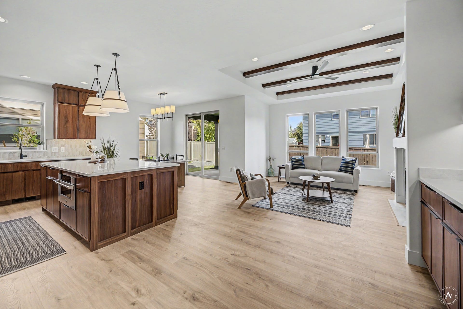 2754 Lone Chief Loop, Helena, MT 59601 Open-concept living area with wood-finish flooring, a kitchen island with built-in appliances, and a living room featuring a recessed ceiling with exposed beams