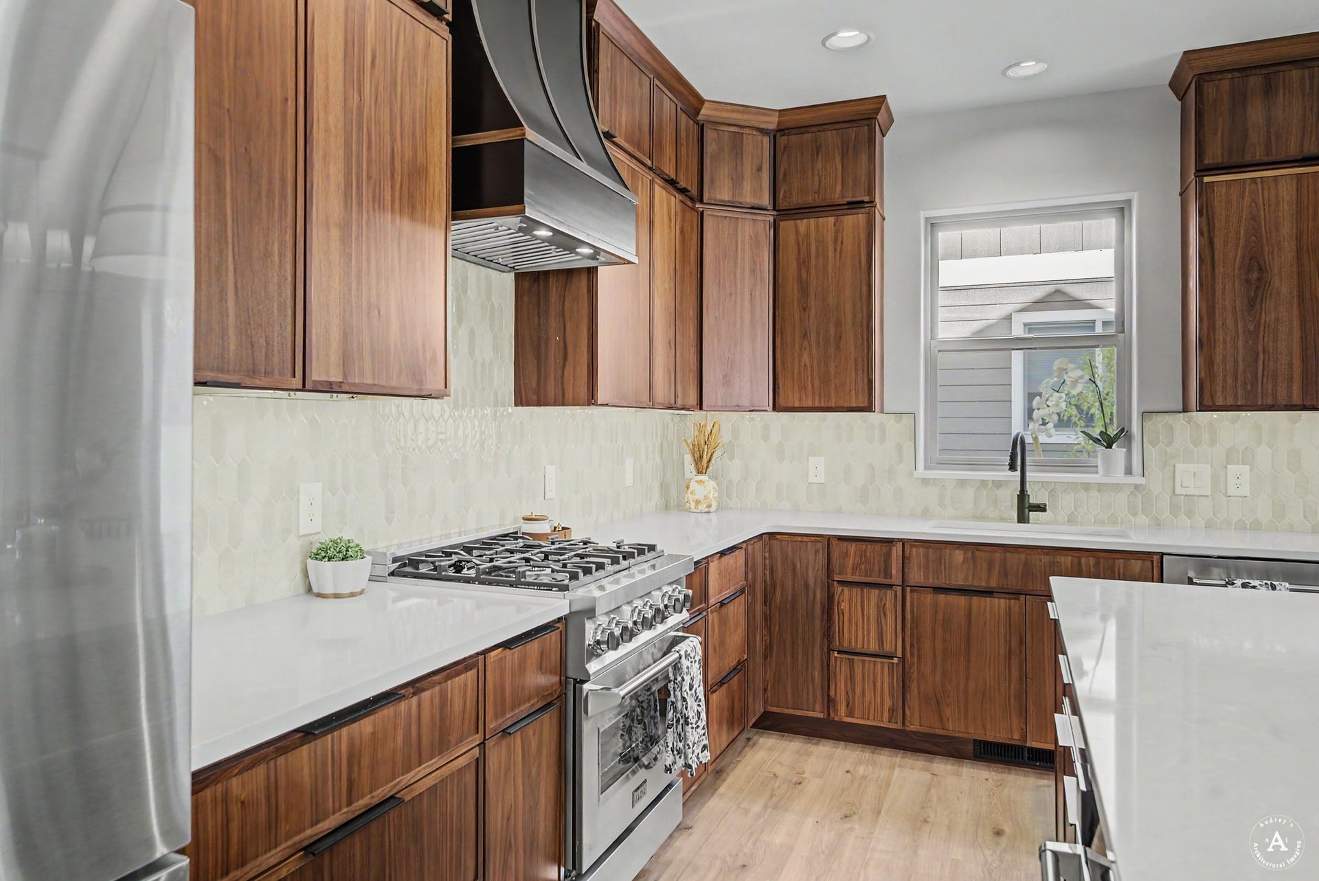 2754 Lone Chief Loop, Helena, MT 59601 Wood cabinetry with integrated handles, stainless steel gas range, coordinating stainless steel range hood, light-toned backsplash, and light-toned countertops