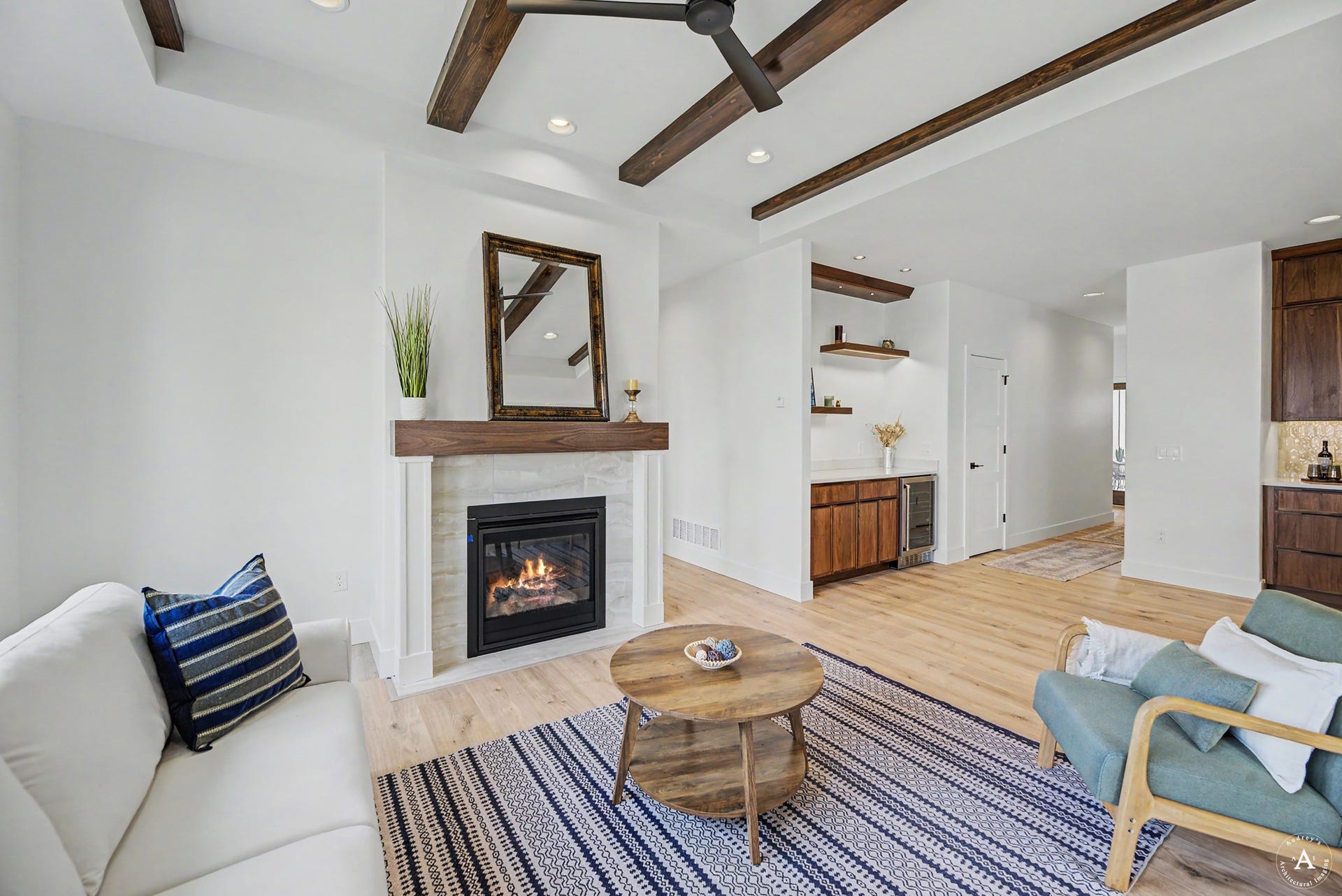 2754 Lone Chief Loop, Helena, MT 59601 Living space featuring a fireplace with a light-toned surround, wood-finish flooring, exposed ceiling beams, and recessed lighting