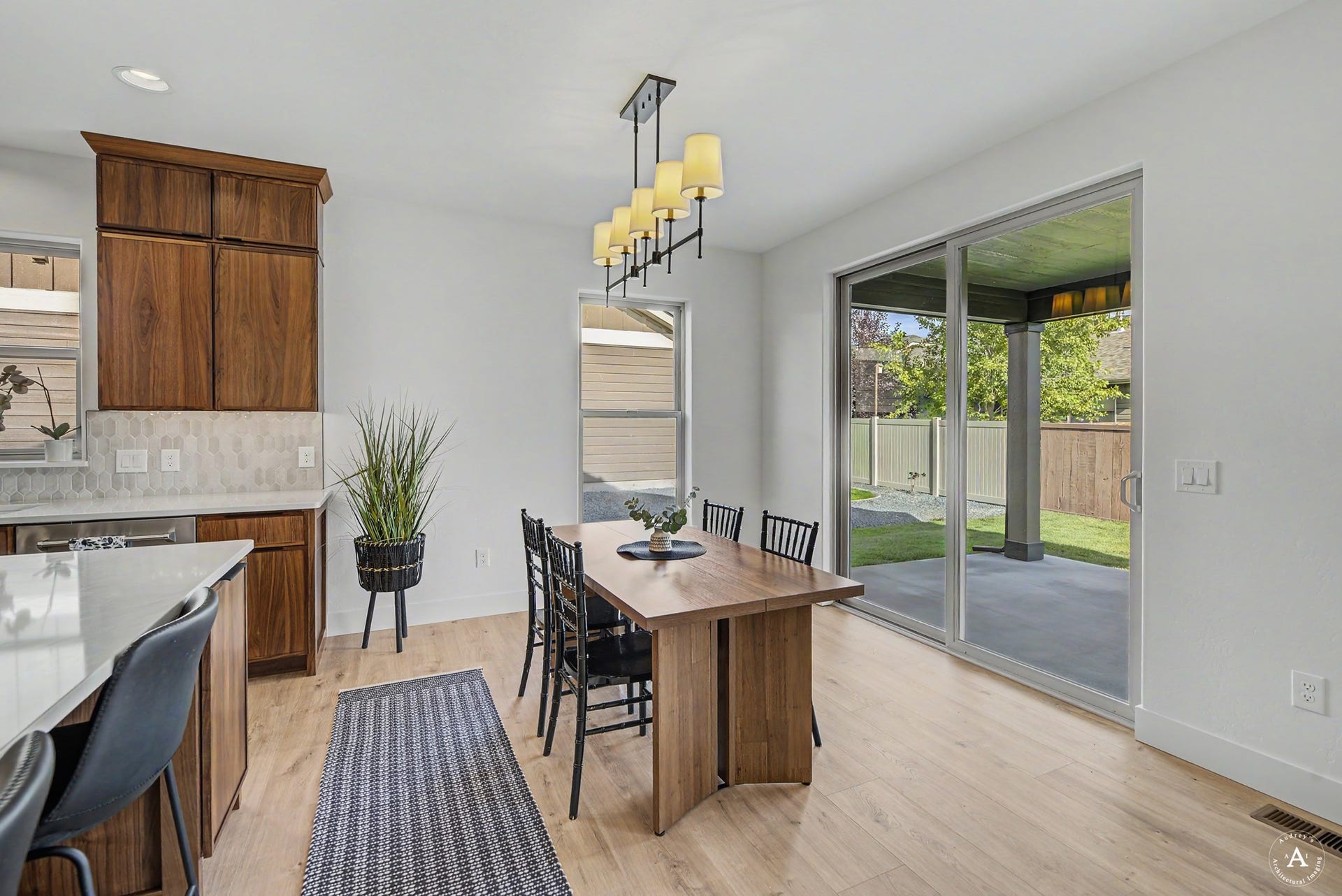 2754 Lone Chief Loop, Helena, MT 59601 Open-concept dining area with wood-finish flooring, a contemporary linear chandelier, and sliding glass doors providing direct access to an outdoor patio