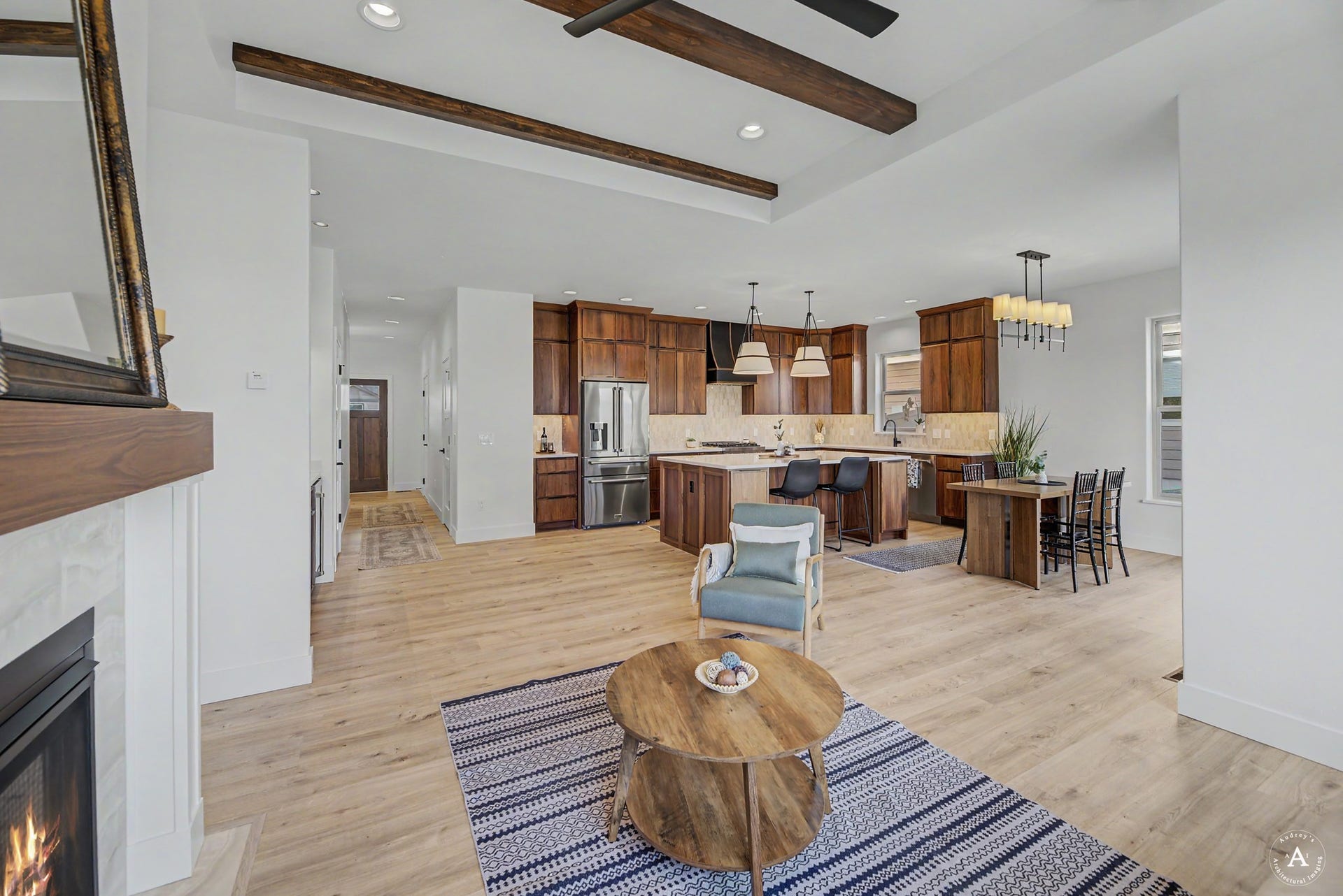 2754 Lone Chief Loop, Helena, MT 59601 Open-concept main living area with wood-finish flooring, a fireplace featuring a wood mantel, and exposed ceiling beams