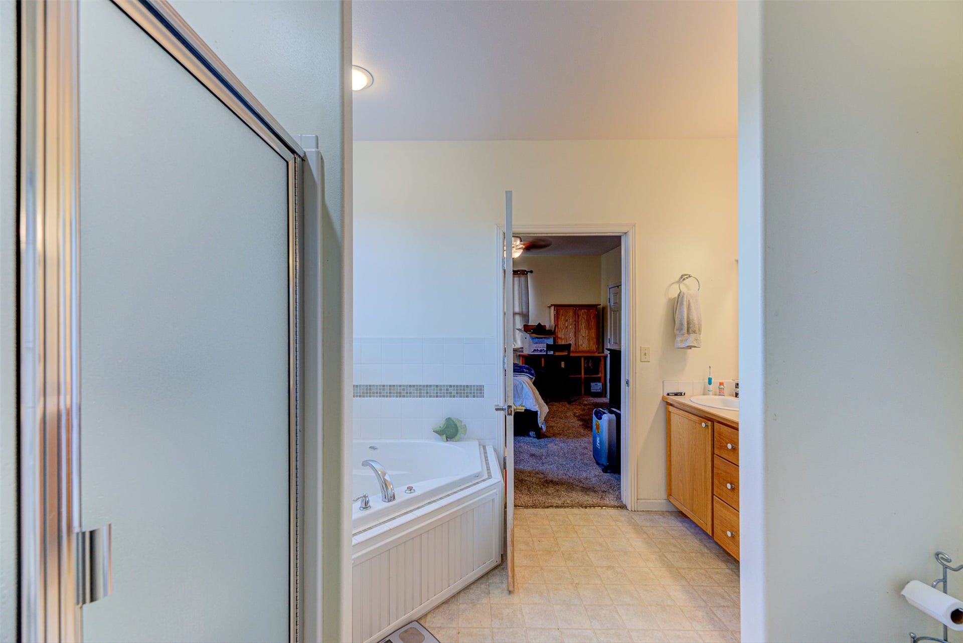 8224 Hillside Drive, Helena, MT 59602 Frosted glass shower enclosure, corner soaking tub, light wood-finish vanity, integrated sink, and light-toned flooring
