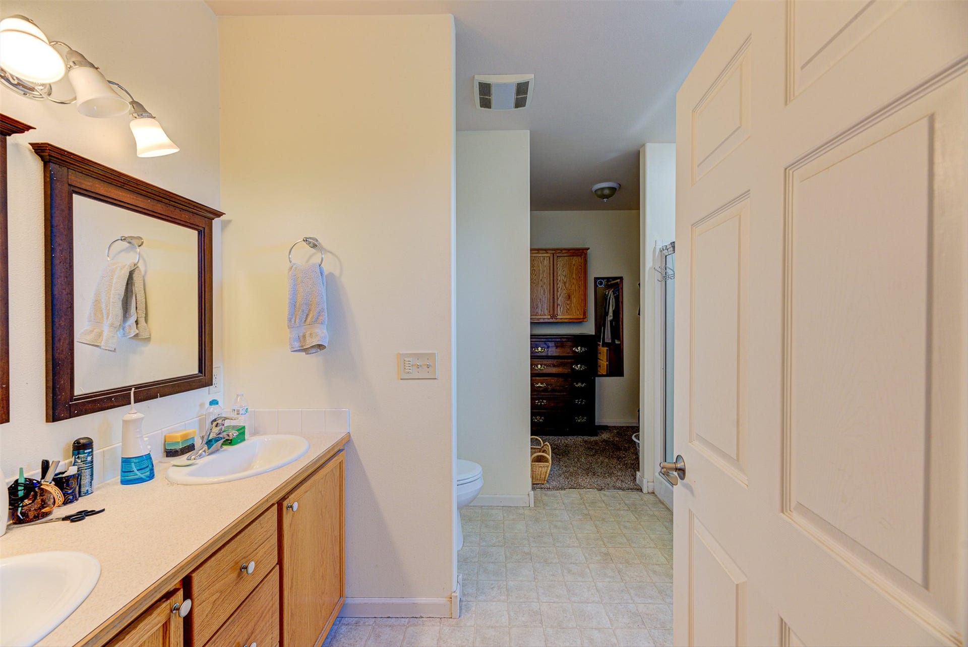 8224 Hillside Drive, Helena, MT 59602 Bathroom featuring dual vanity sinks, light wood-finish cabinetry, and a framed mirror