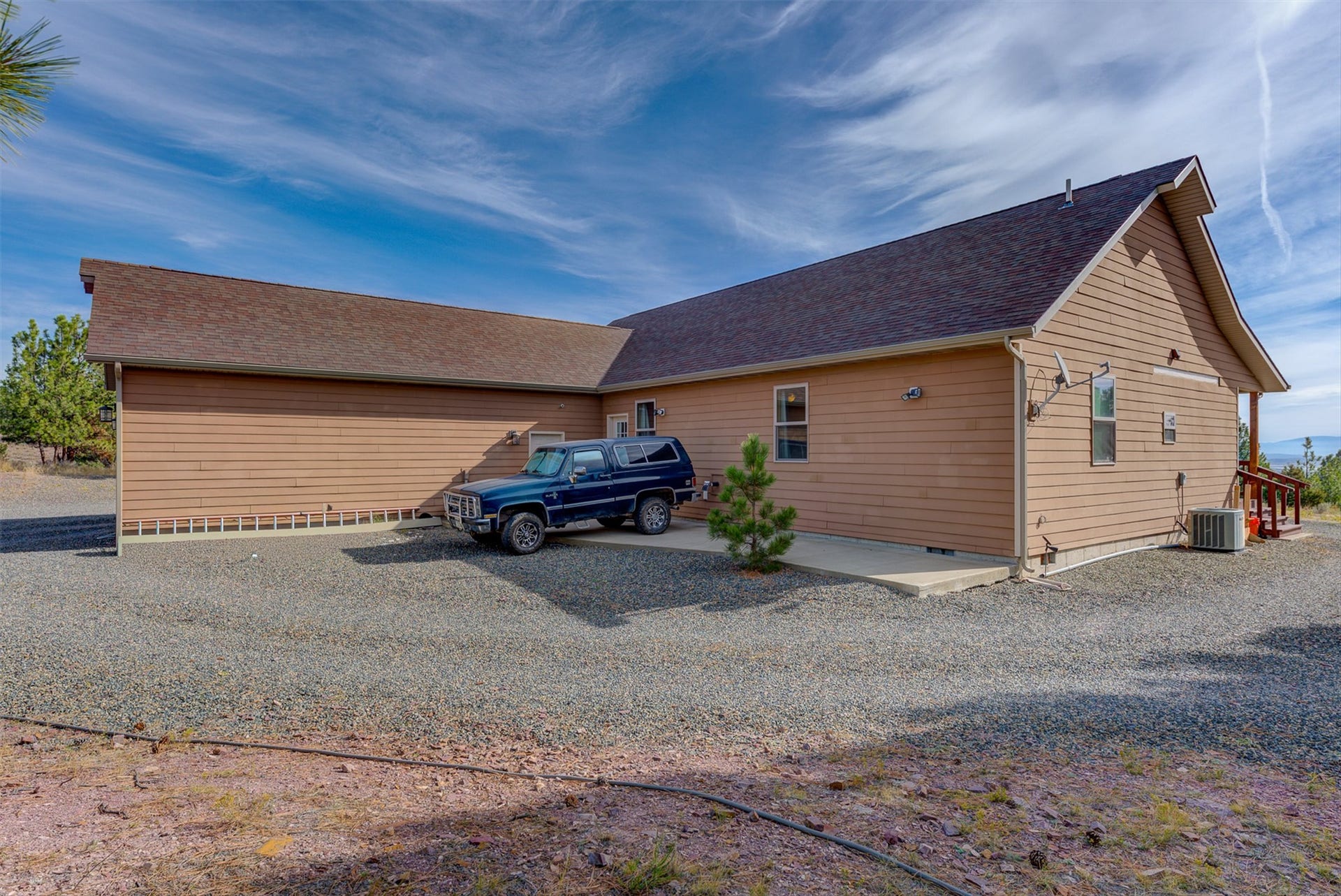 8224 Hillside Drive, Helena, MT 59602 Siding exterior with multiple windows, pitched roof, and gravel ground cover