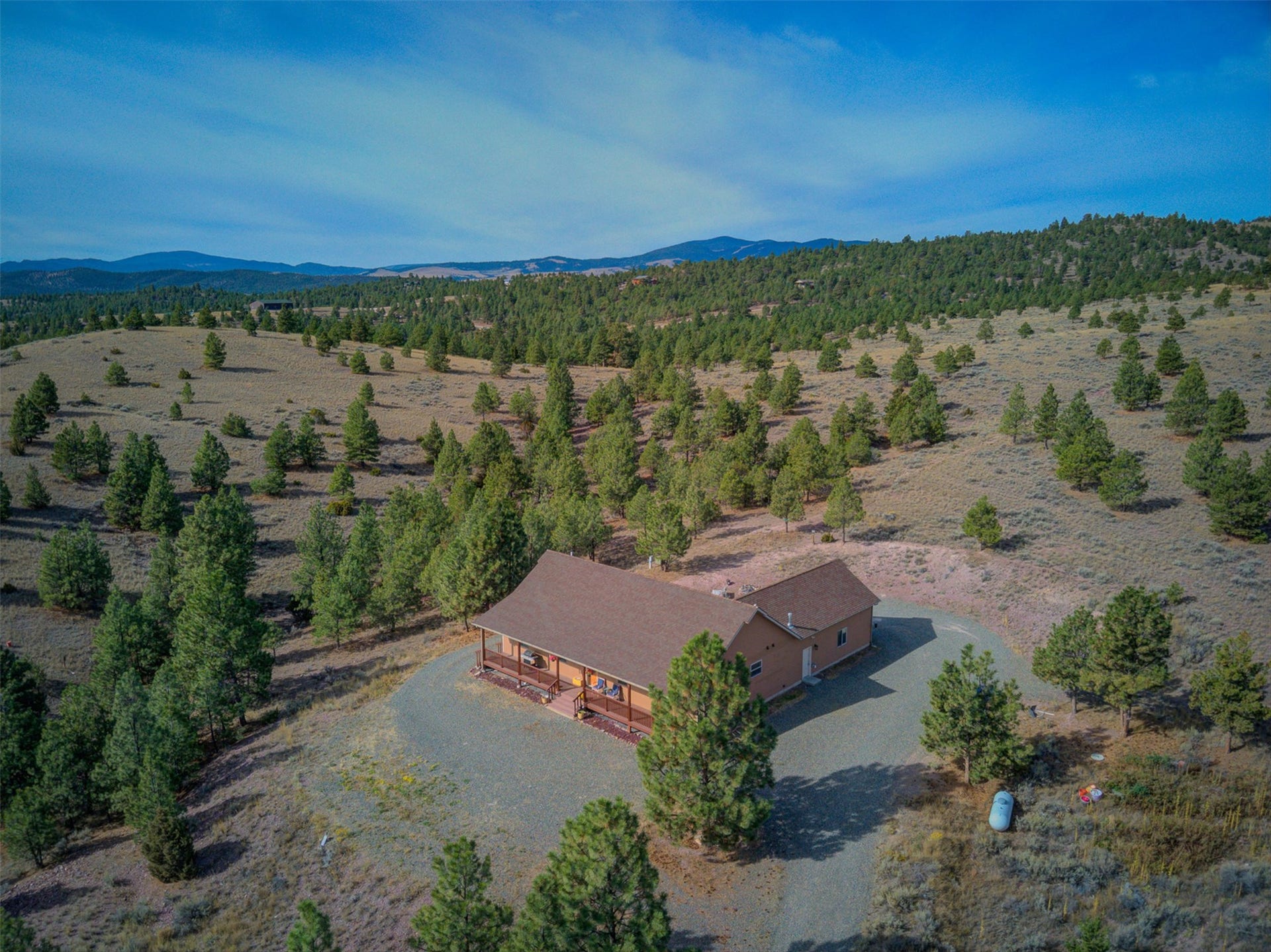 8224 Hillside Drive, Helena, MT 59602 Ranch-style residence with a covered front porch, a gravel driveway, and a natural landscape with scattered trees