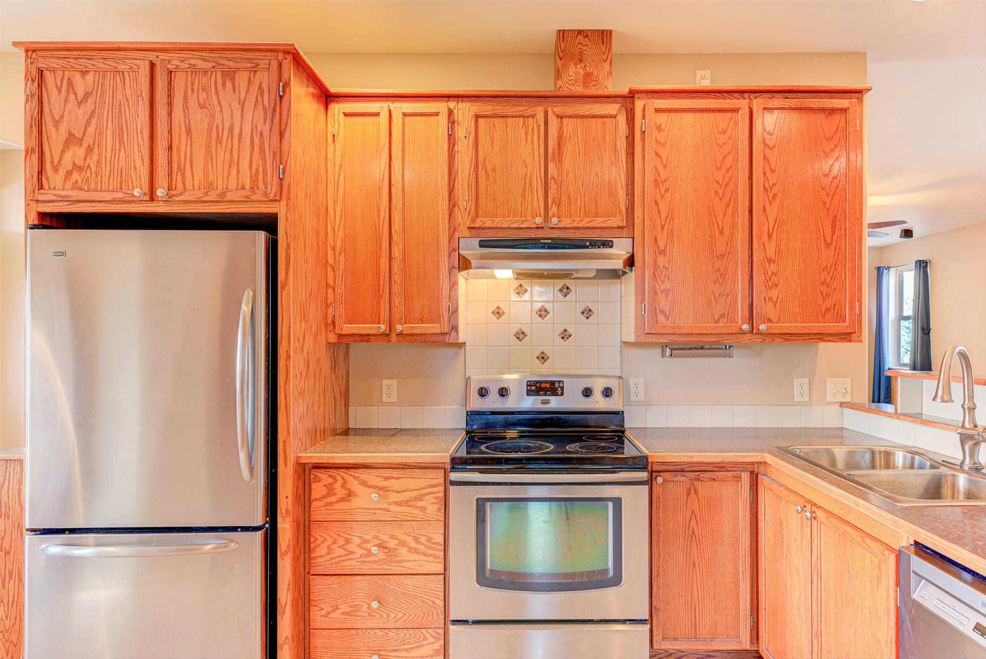 8224 Hillside Drive, Helena, MT 59602 Wood-finish cabinetry, stainless steel appliances, tile backsplash, laminate countertops, and a double basin sink