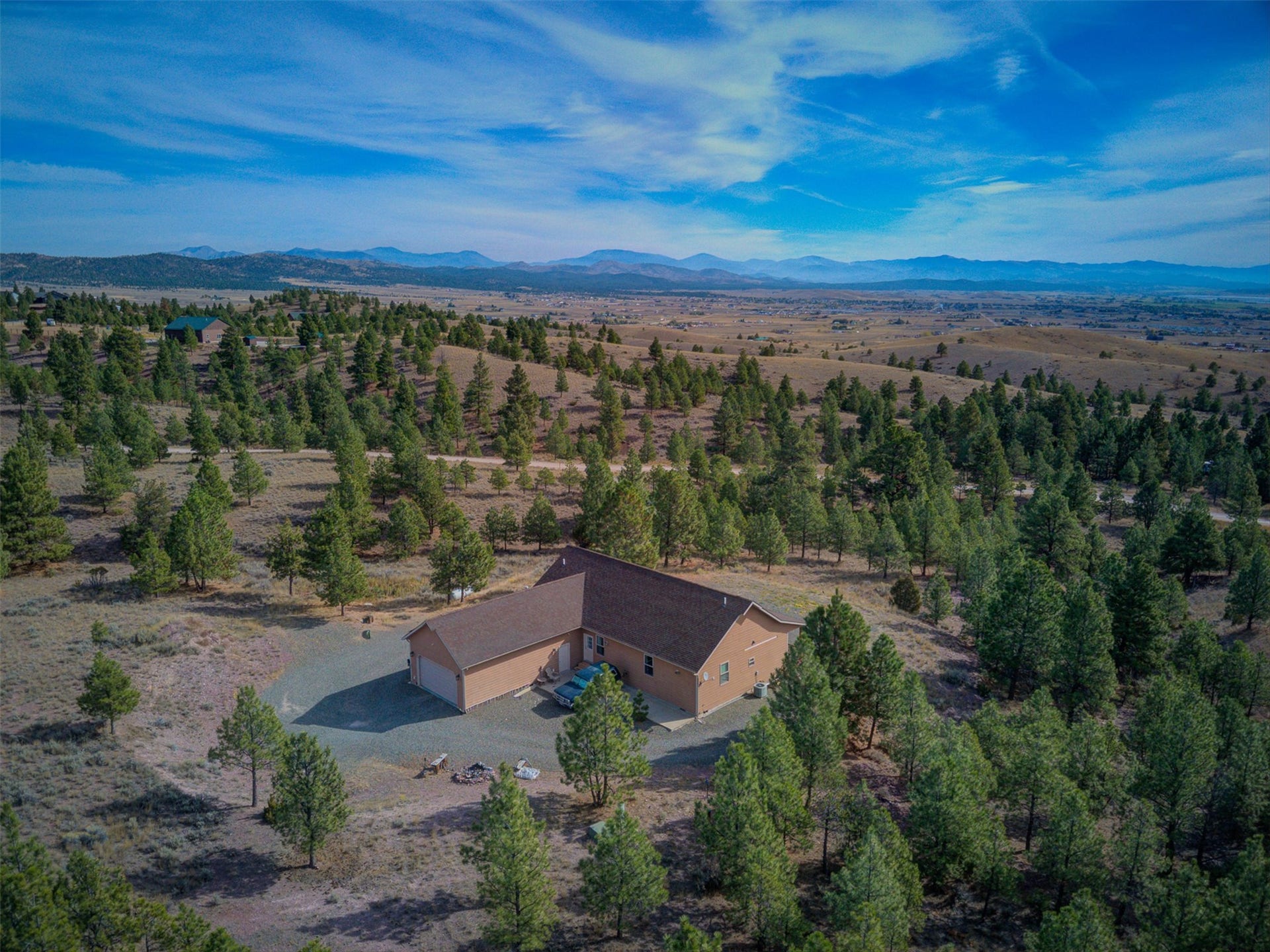 8224 Hillside Drive, Helena, MT 59602 Ranch-style residence featuring an attached garage, gravel driveway, and surrounding mature trees