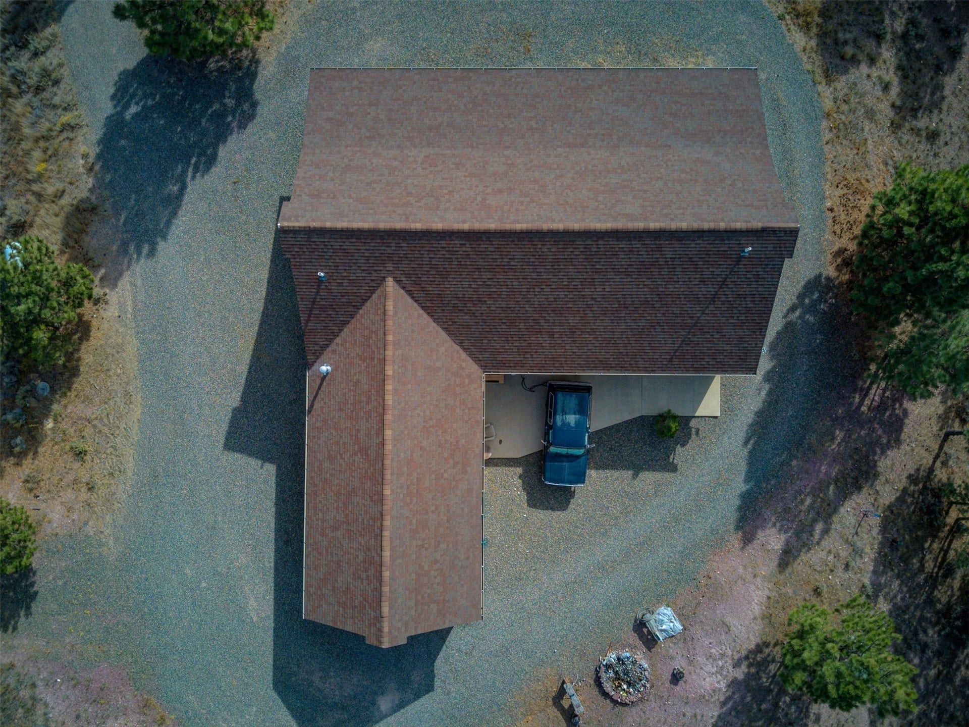 8224 Hillside Drive, Helena, MT 59602 Gable roofline with asphalt shingles, gravel driveway, covered carport, and outdoor fire pit area