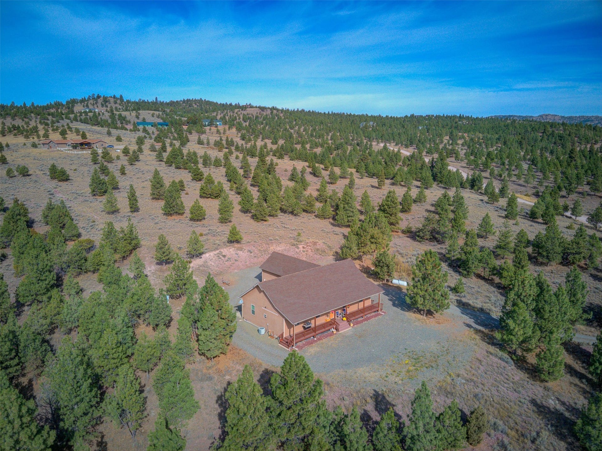 8224 Hillside Drive, Helena, MT 59602 Expansive natural landscape with scattered trees, a single-story residence, and a gravel driveway