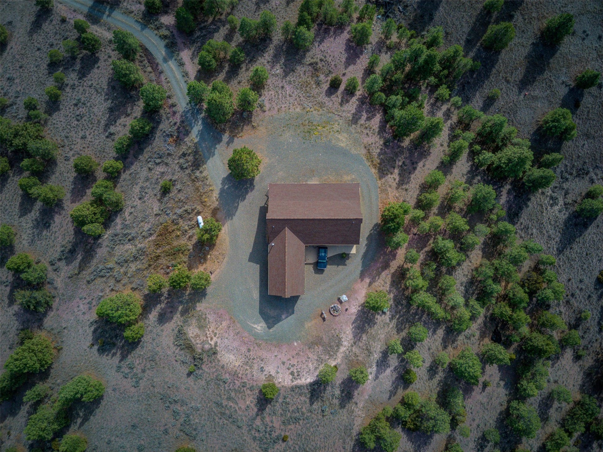 8224 Hillside Drive, Helena, MT 59602 Brown shingle roof structure with an attached garage, surrounded by a gravel driveway and natural landscaping