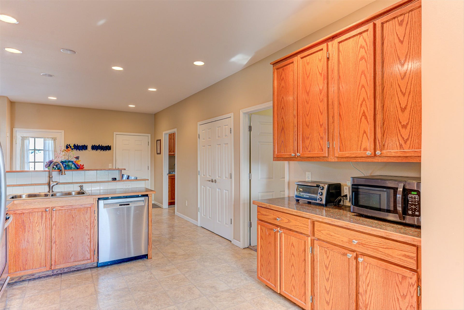 8224 Hillside Drive, Helena, MT 59602 Kitchen featuring wood cabinetry, stainless steel dishwasher, tile flooring, recessed lighting, and a dual basin sink