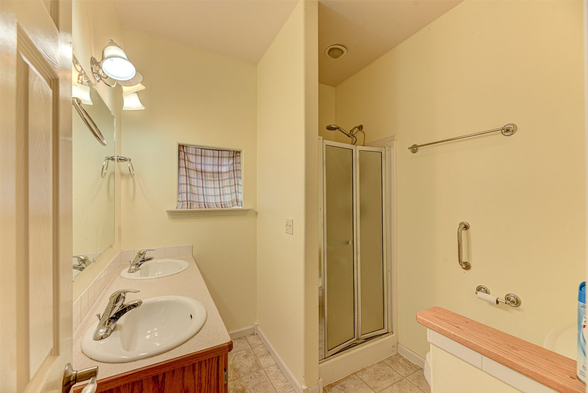 8224 Hillside Drive, Helena, MT 59602 Dual vanity with integrated sinks, wood-finish cabinetry, built-in mirror, and enclosed shower