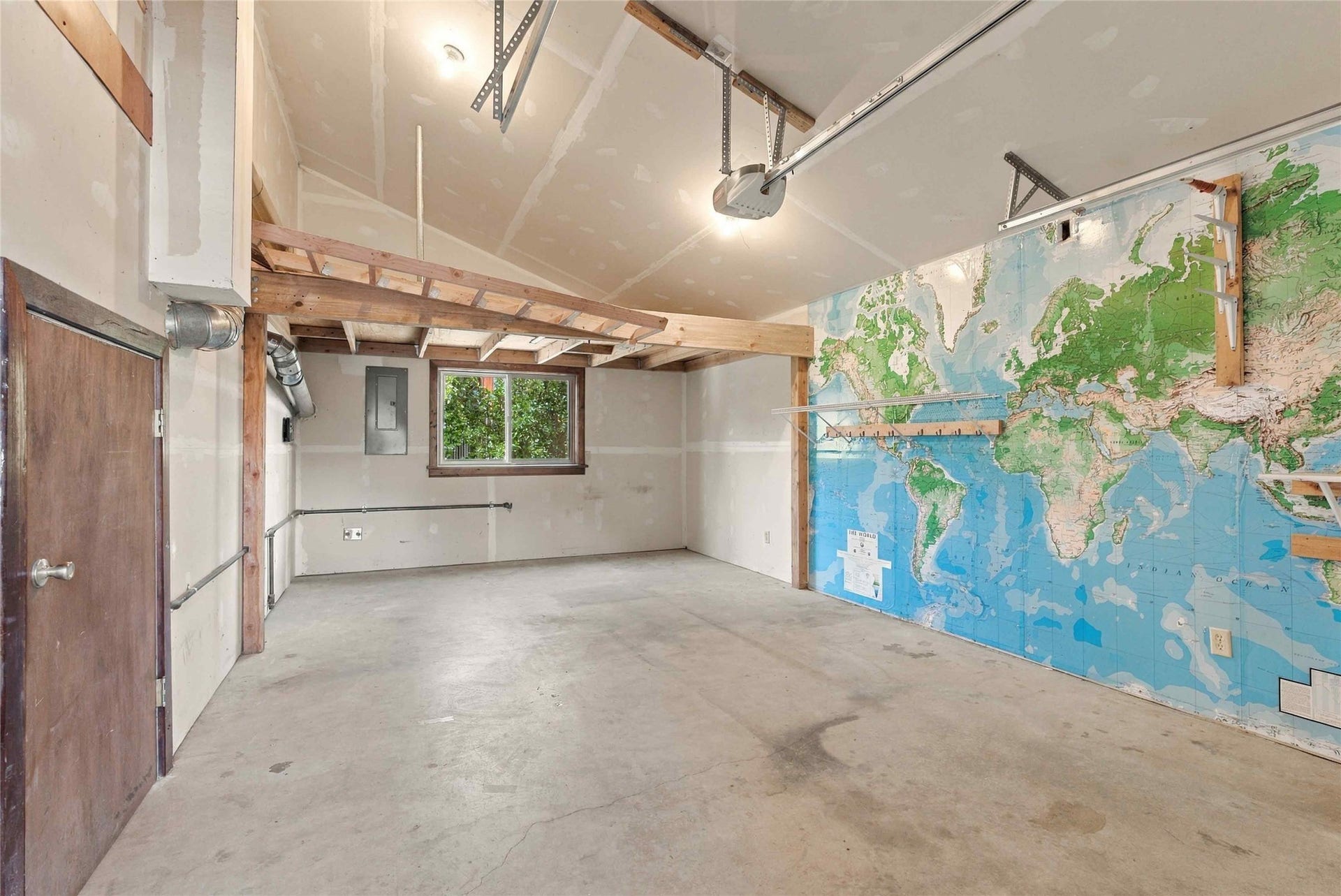 Spacious utility room featuring a concrete floor, high vaulted ceiling, and an integrated overhead storage area