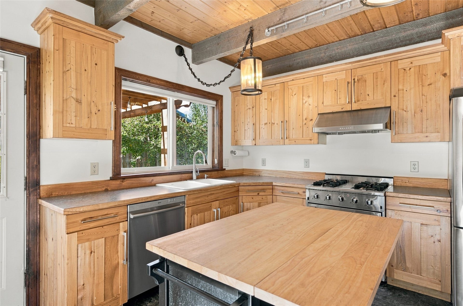 Kitchen featuring wood cabinetry, stainless steel appliances, wood-finish countertops, and exposed beam ceiling
