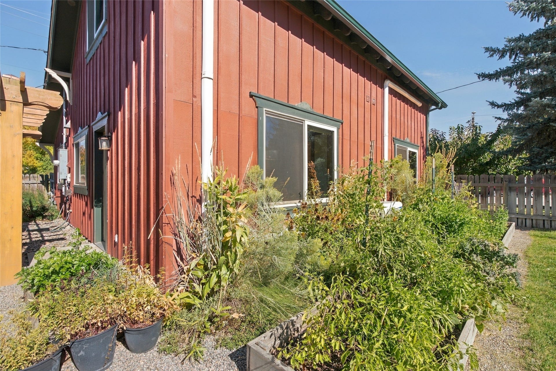 Board and batten exterior with dark trim windows, exterior lighting, and raised garden beds