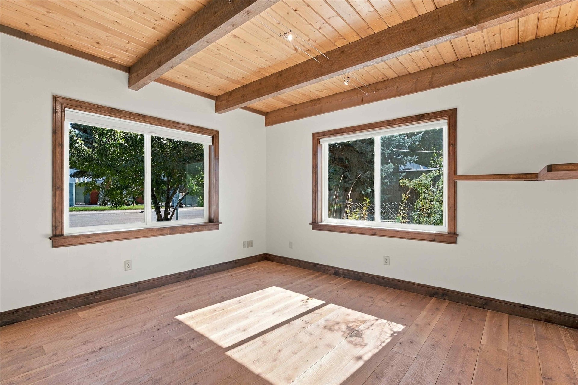 Wood-finish flooring, exposed wood beams, wood-paneled ceiling, and dual windows with wood trim
