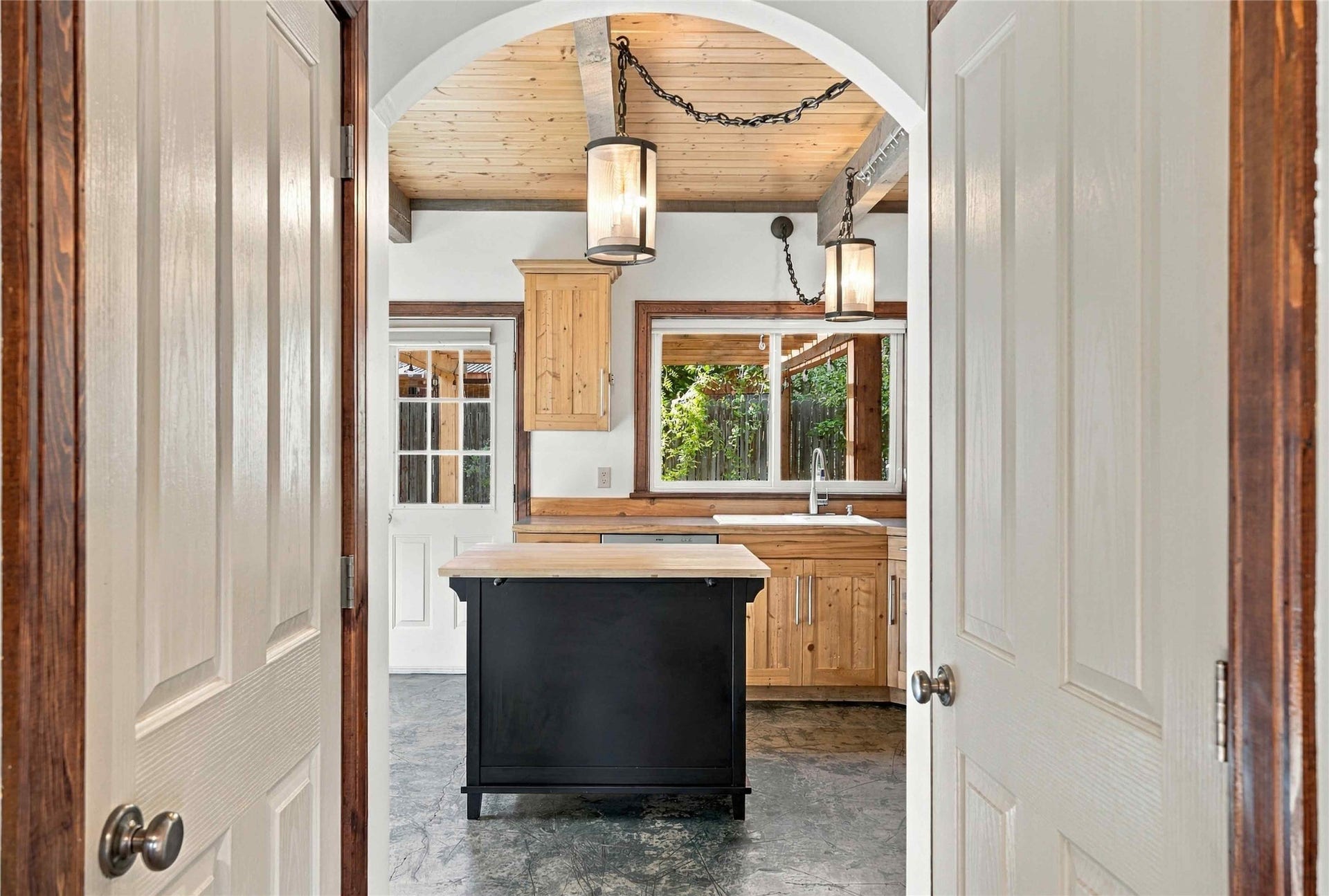 Arched entryway with a wood-finish ceiling, exposed wood beams, and a pair of pendant light fixtures