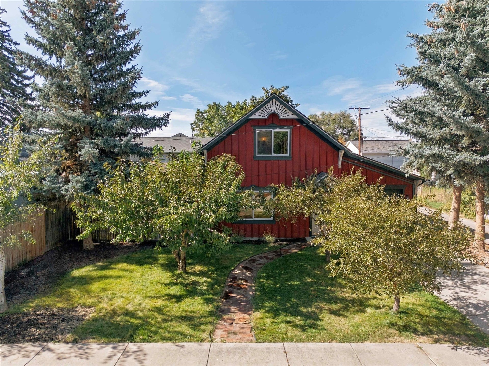Red exterior siding with white trim, featuring a gabled roofline and decorative gable pediment