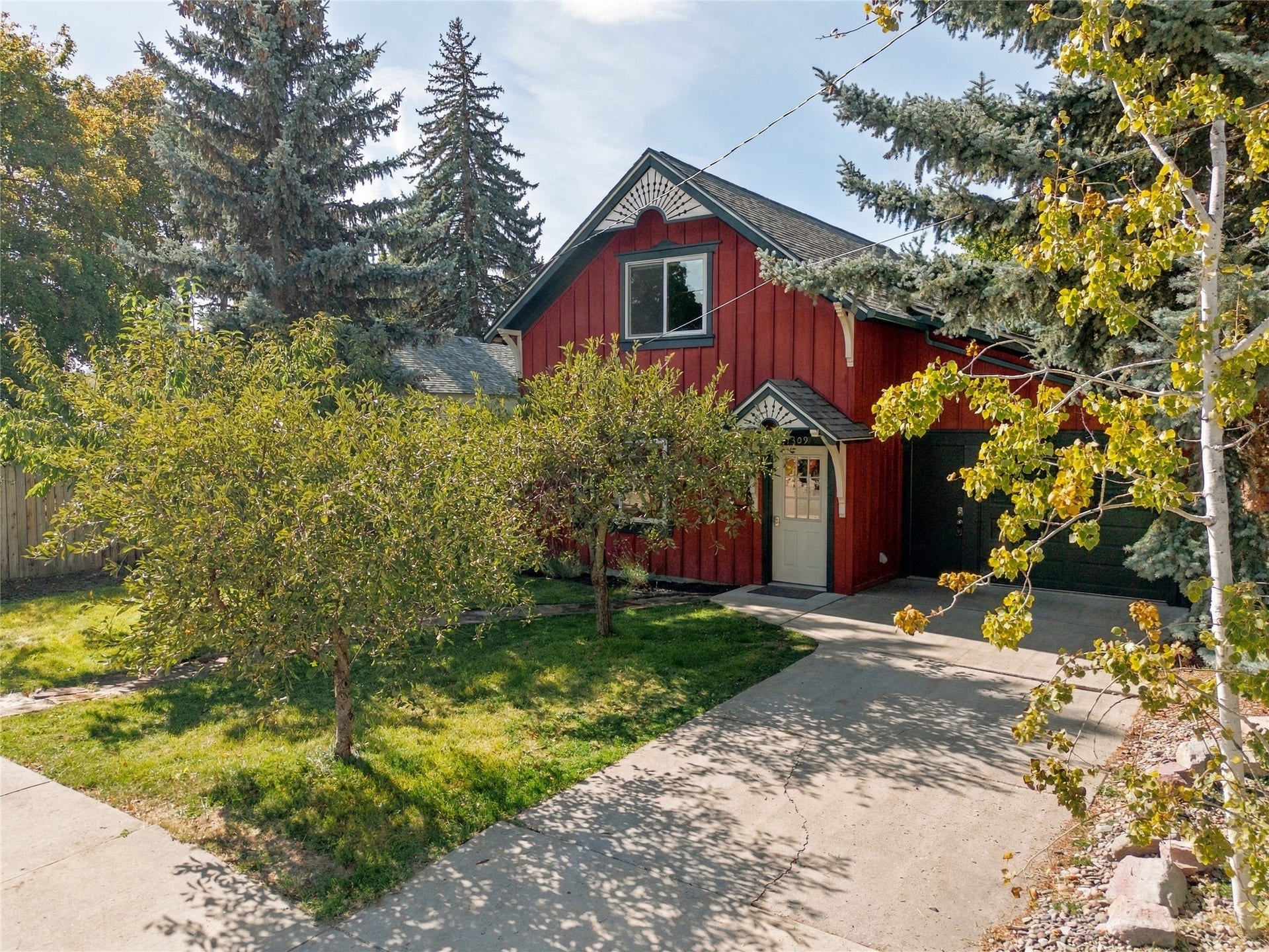 Red-sided exterior with decorative trim, gabled roofline, attached garage, and a light-colored entry door