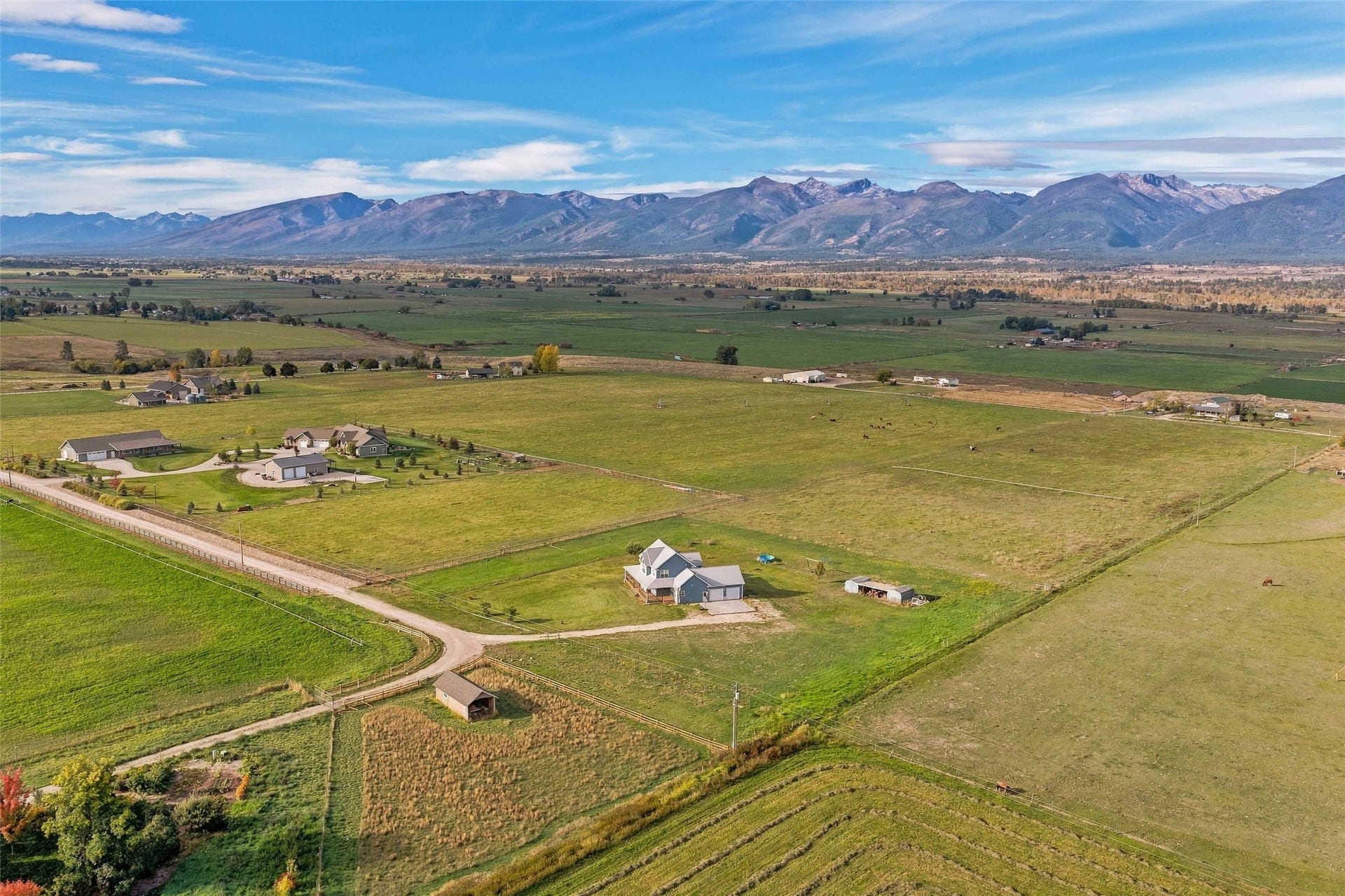 Expansive rural property featuring a main residence, multiple auxiliary structures, and surrounding agricultural land