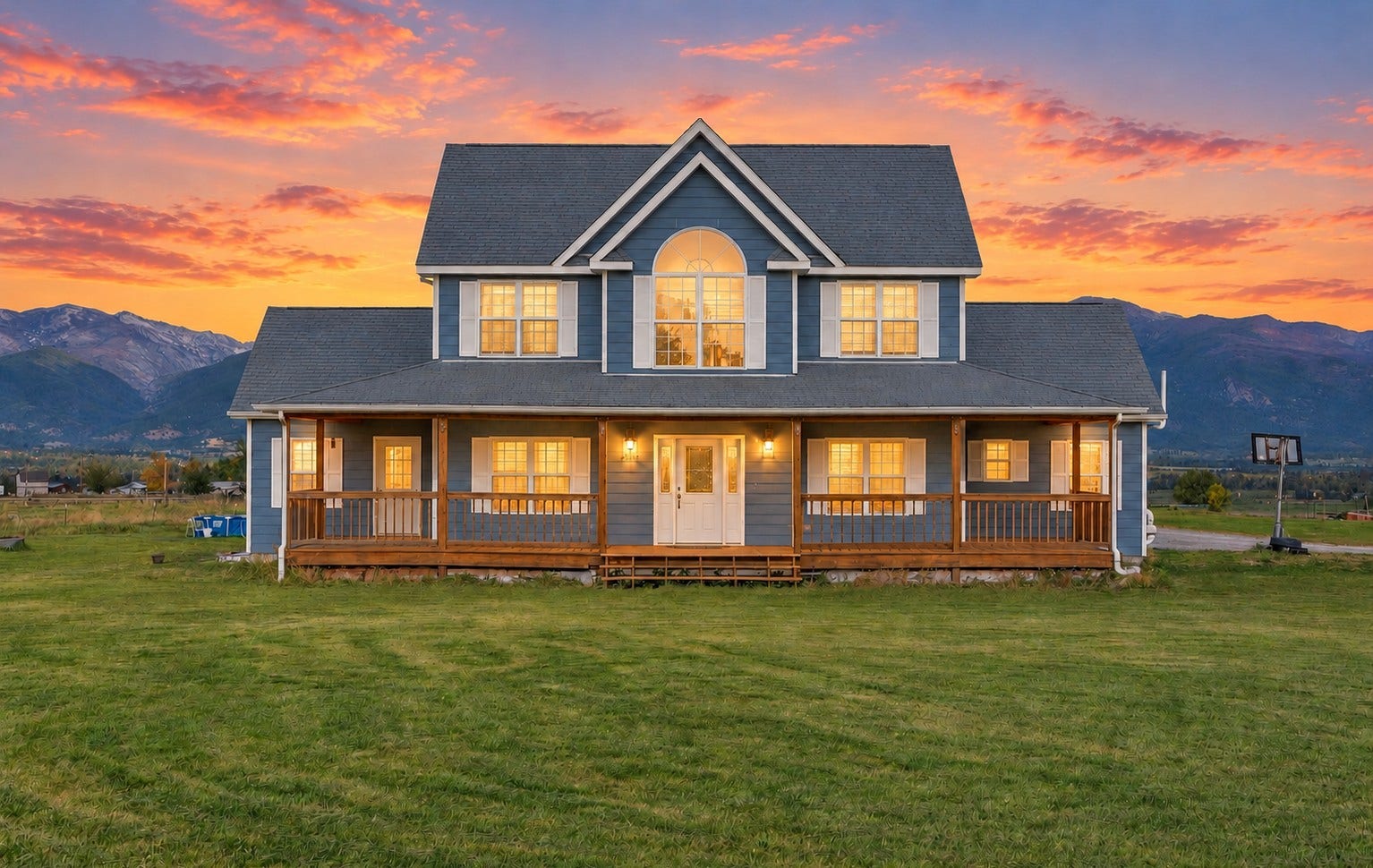 Expansive green lawn with a two-story residence featuring a covered porch, multiple windows, and a prominent arched window on the upper level