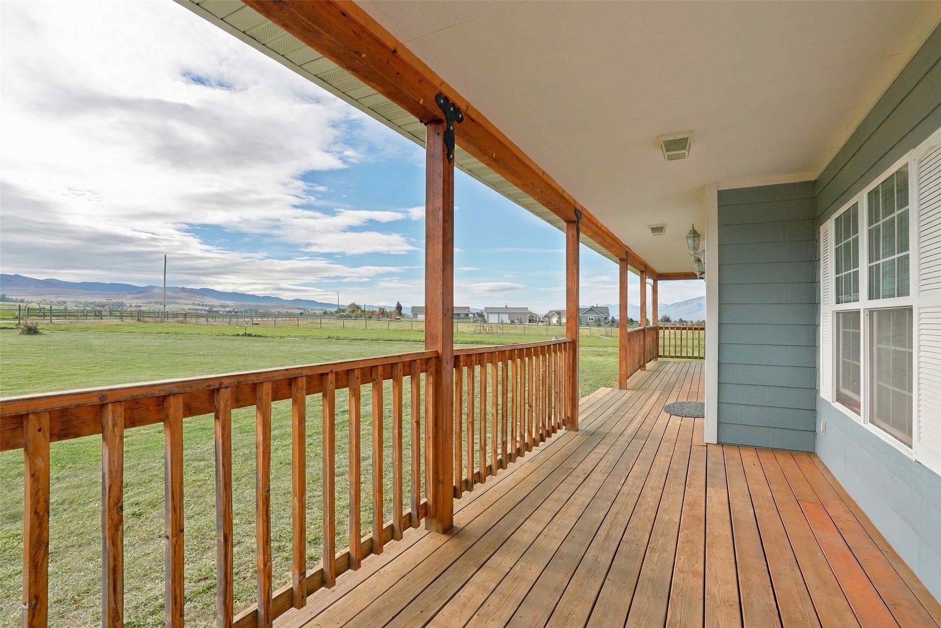 Expansive covered porch featuring wood decking and railings