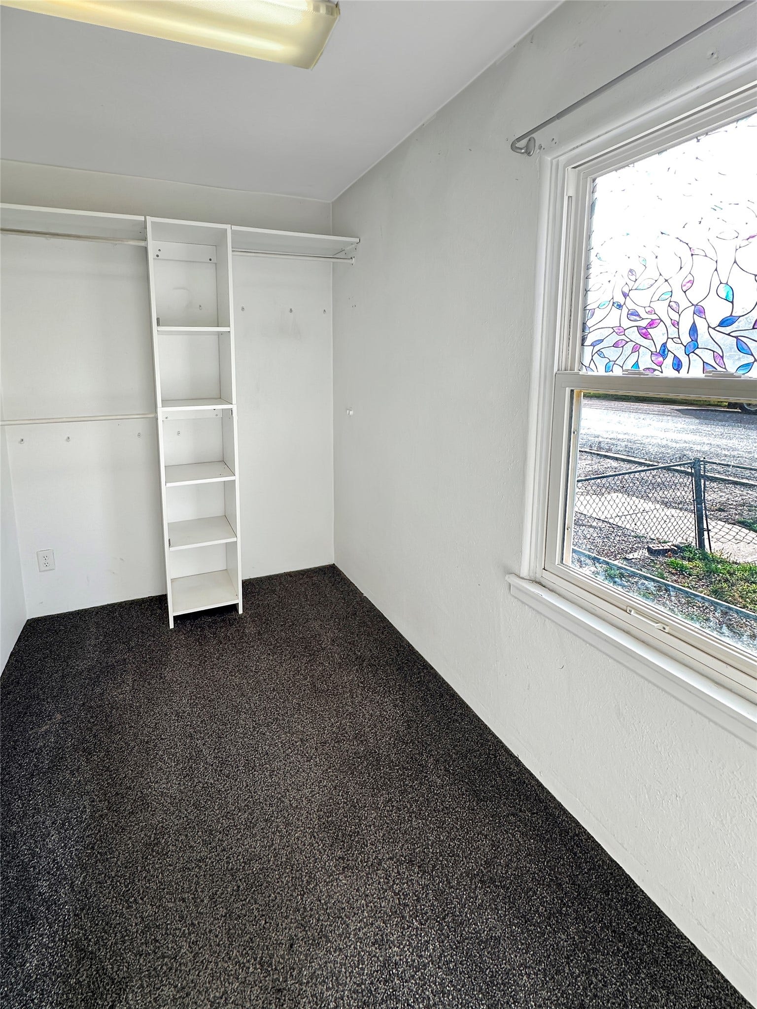 1123 2nd Street N, Shelby, MT 59474 Built-in shelving unit, white walls, dark carpet flooring, and a single window with decorative film