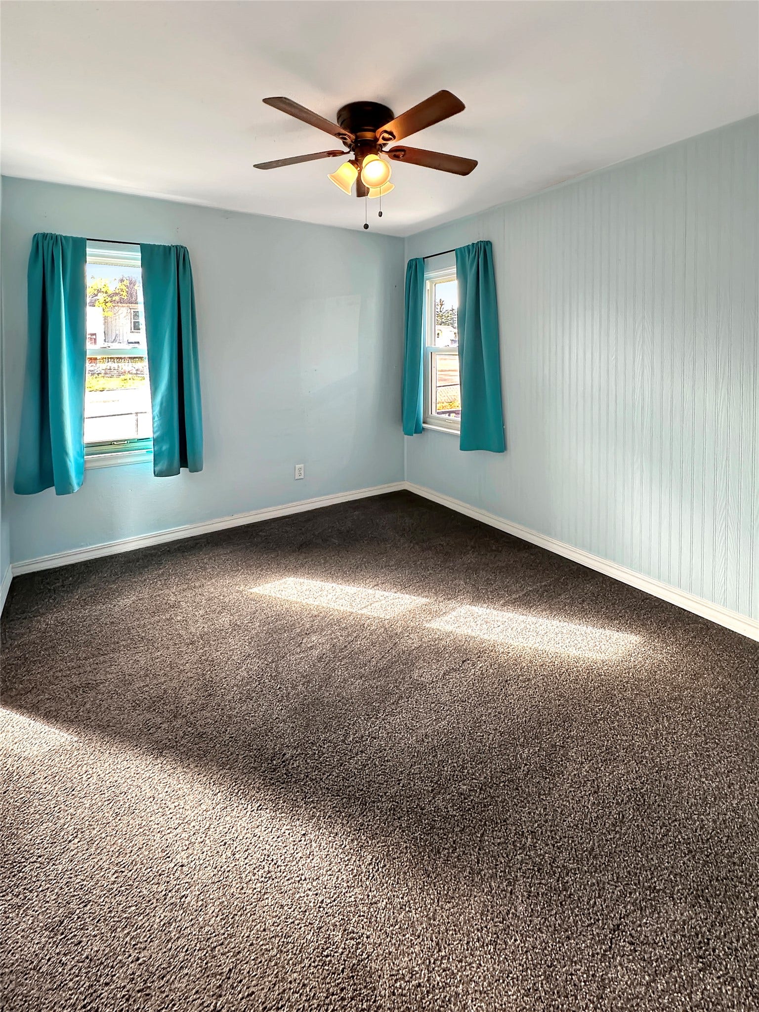 1123 2nd Street N, Shelby, MT 59474 Carpeted room with a ceiling fan, two windows, and light blue walls